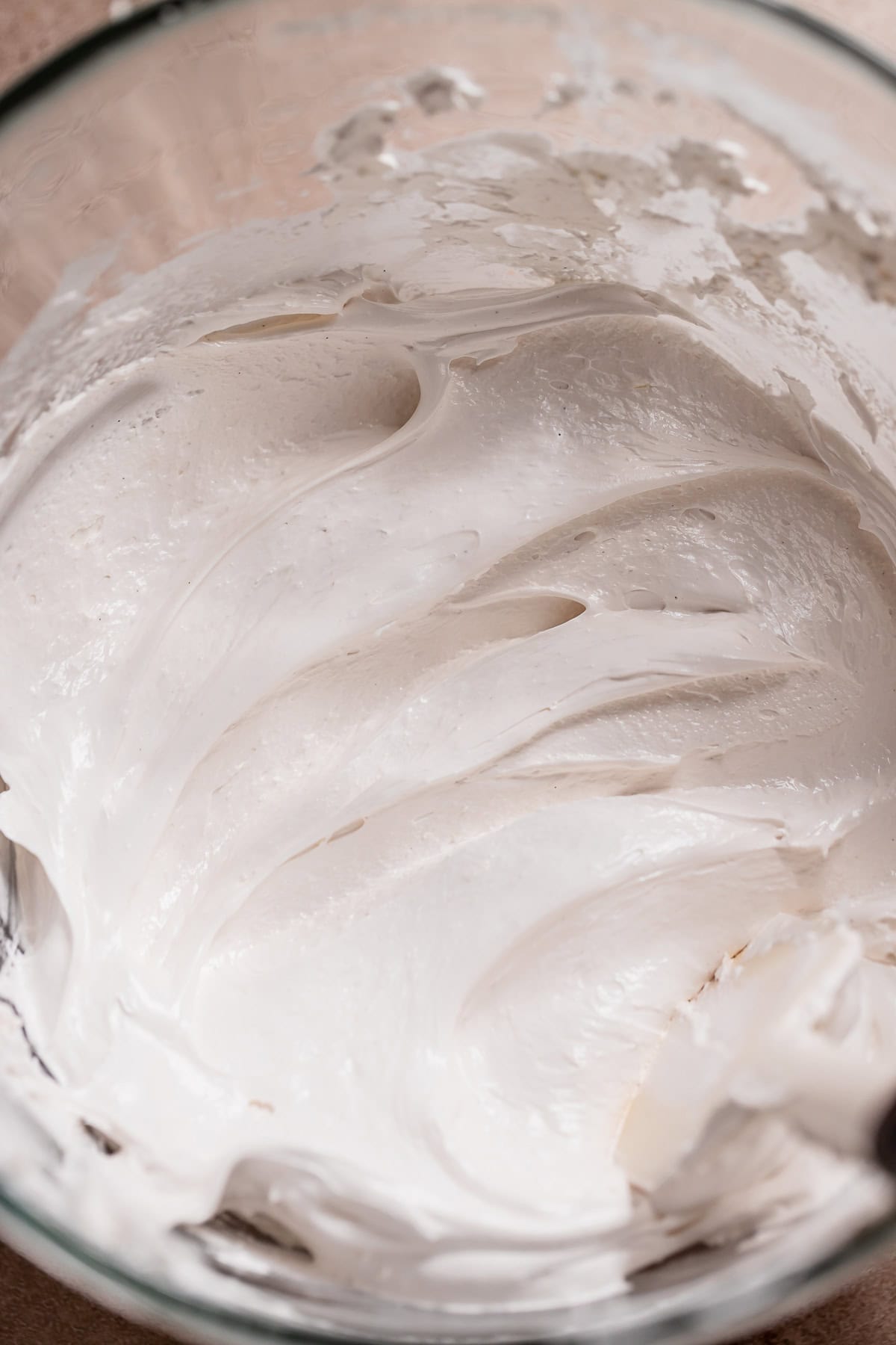 Whipped marshmallow fluff filling in a glass mixer bowl.