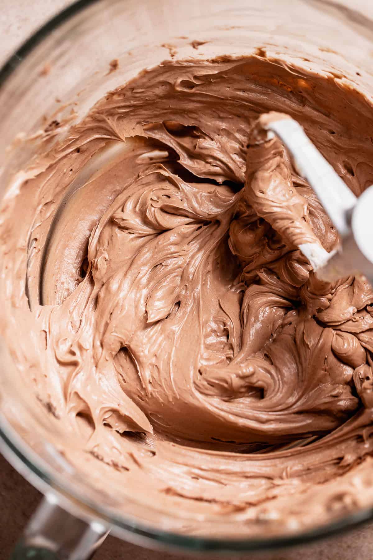 Milk chocolate buttercream frosting in a glass mixer bowl.
