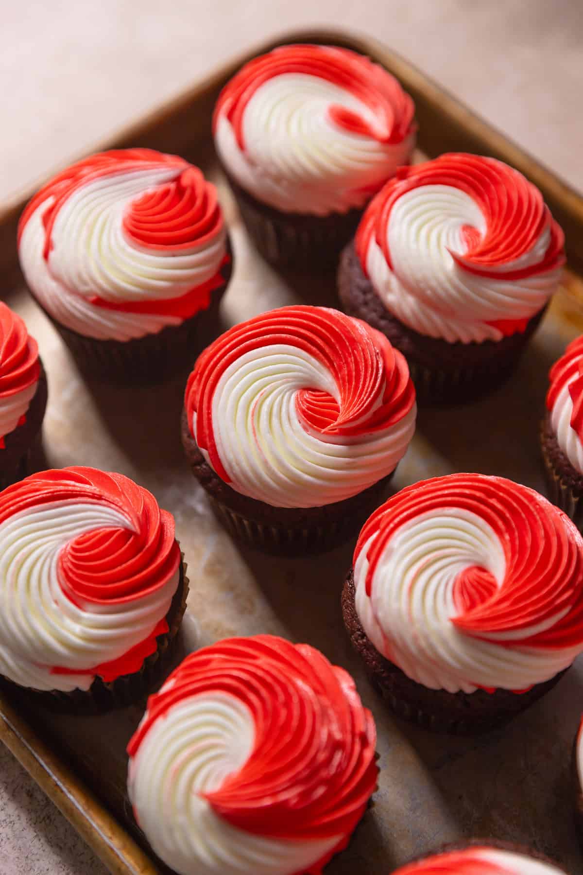 Chocolate cupcakes with swirled peppermint frosting on a baking tray.