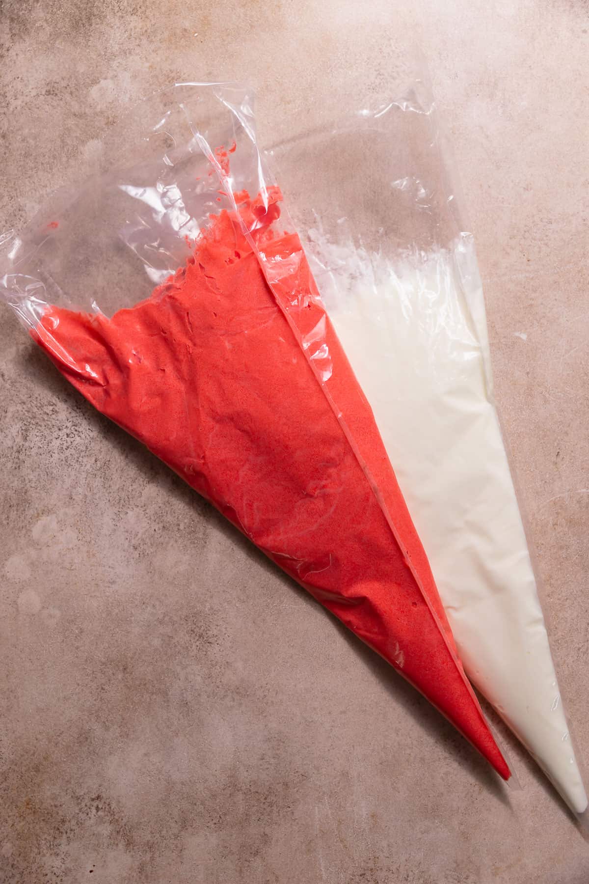 Two piping bags filled with white and red peppermint frosting.
