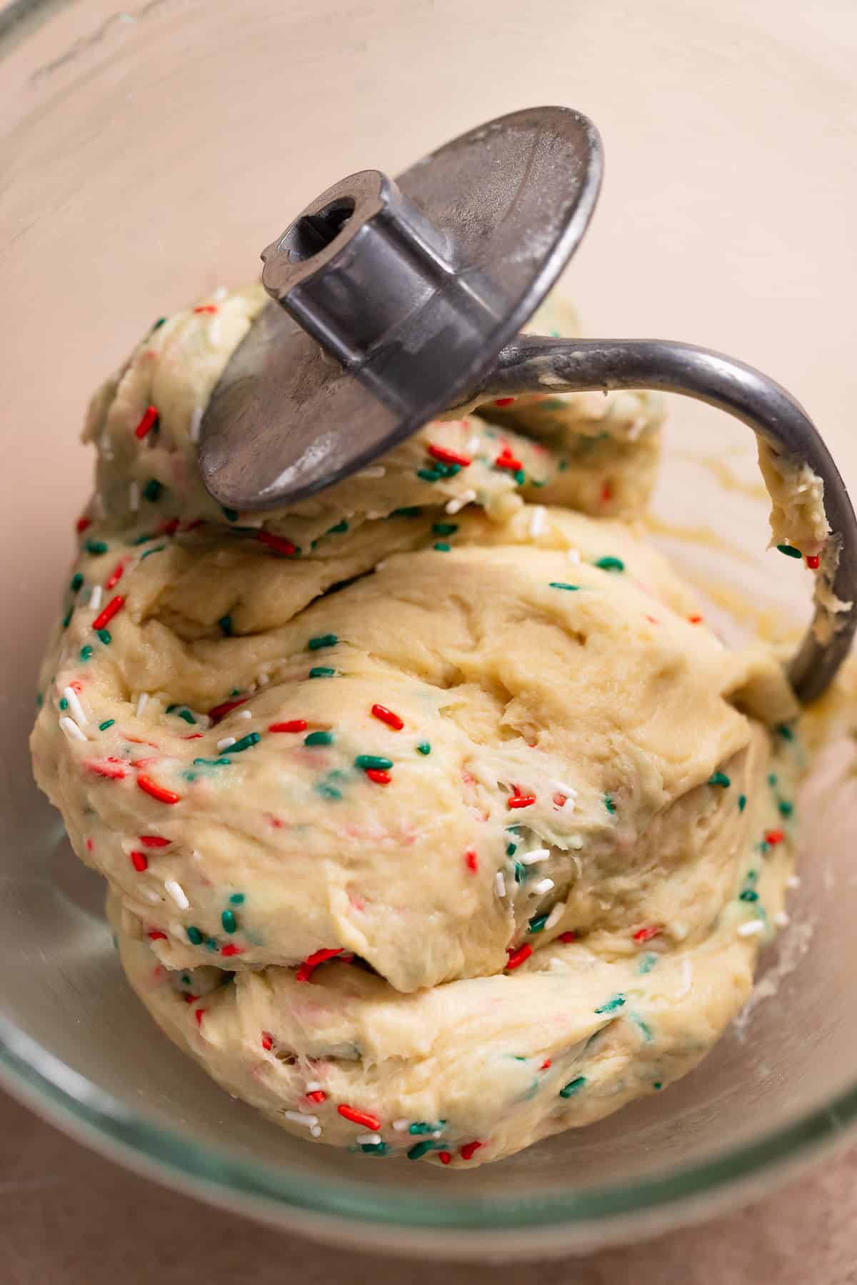 Sweet roll dough kneaded with green and red sprinkles in a mixer bowl.