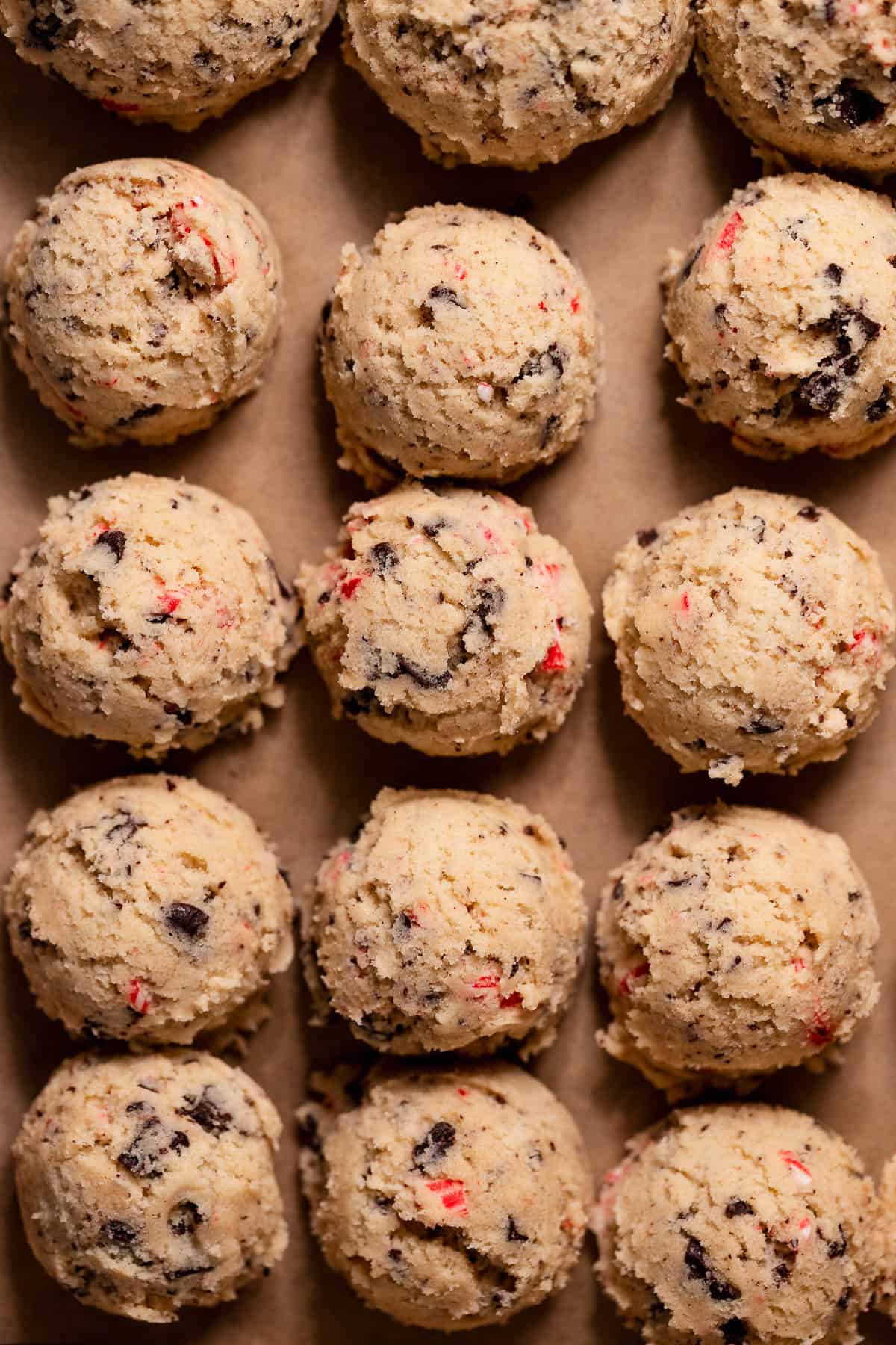 Scoops of peppermint chocolate chip cookie dough arranged in neat rows on parchment paper.