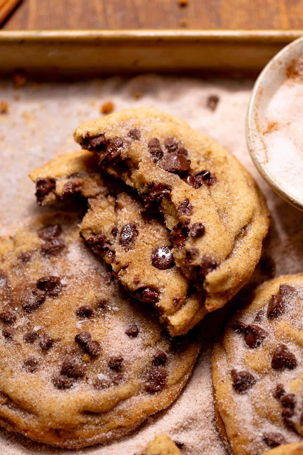 A chocolate chip snickerdoodle cookie broken in half with a soft, gooey center.