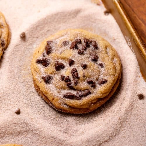 Chocolate chip snickerdoodle cookie coated in cinnamon sugar on a baking sheet.