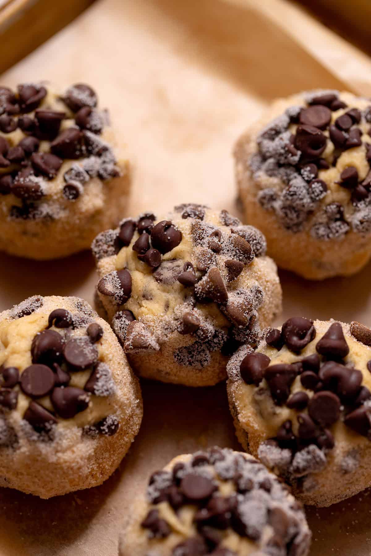Chocolate chip snickerdoodle dough balls coated in cinnamon sugar on a baking tray.