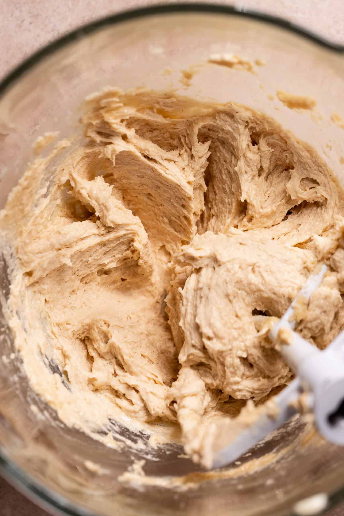 Creamed butter, sugar, and egg mixture in a glass mixing bowl with a paddle attachment.