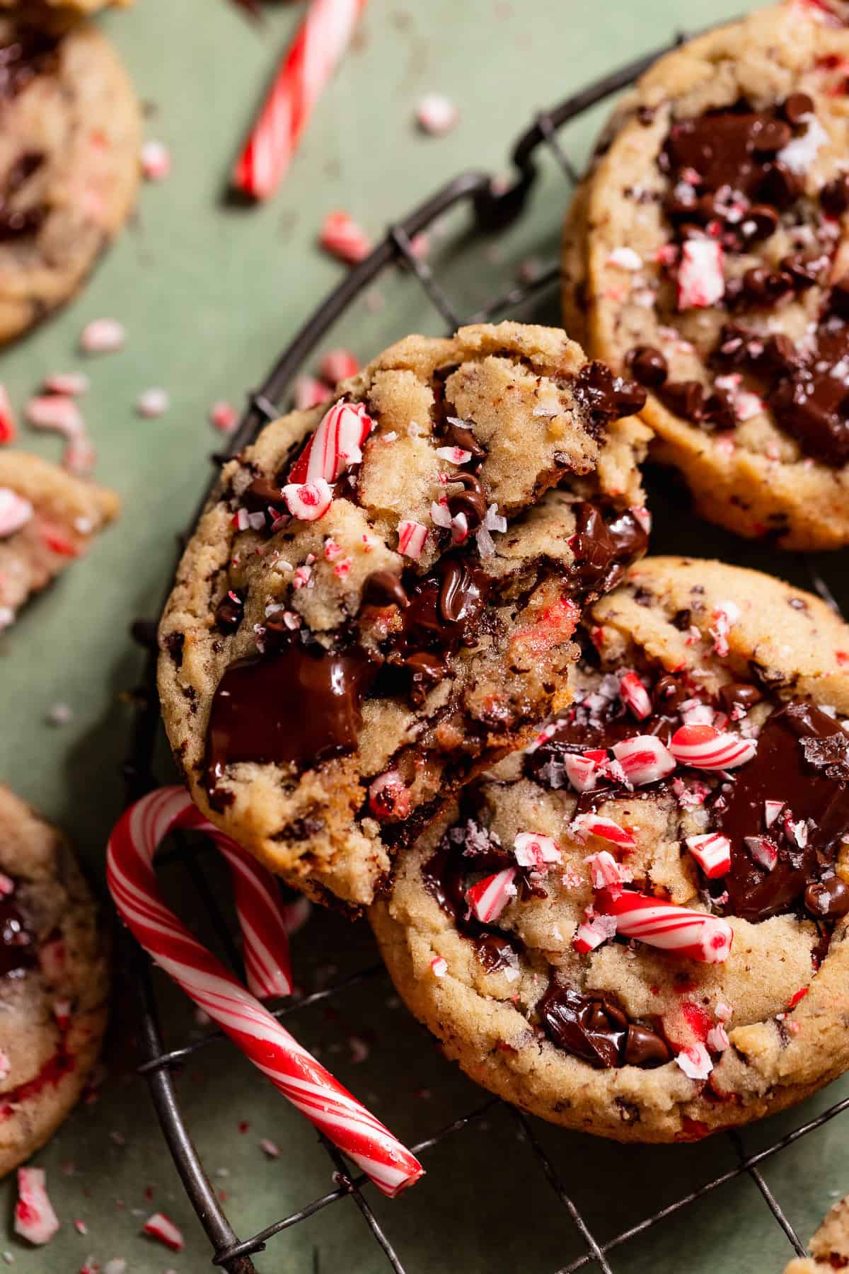 Peppermint chocolate chip cookie broken in half with melted chocolate and crushed candy canes on top.