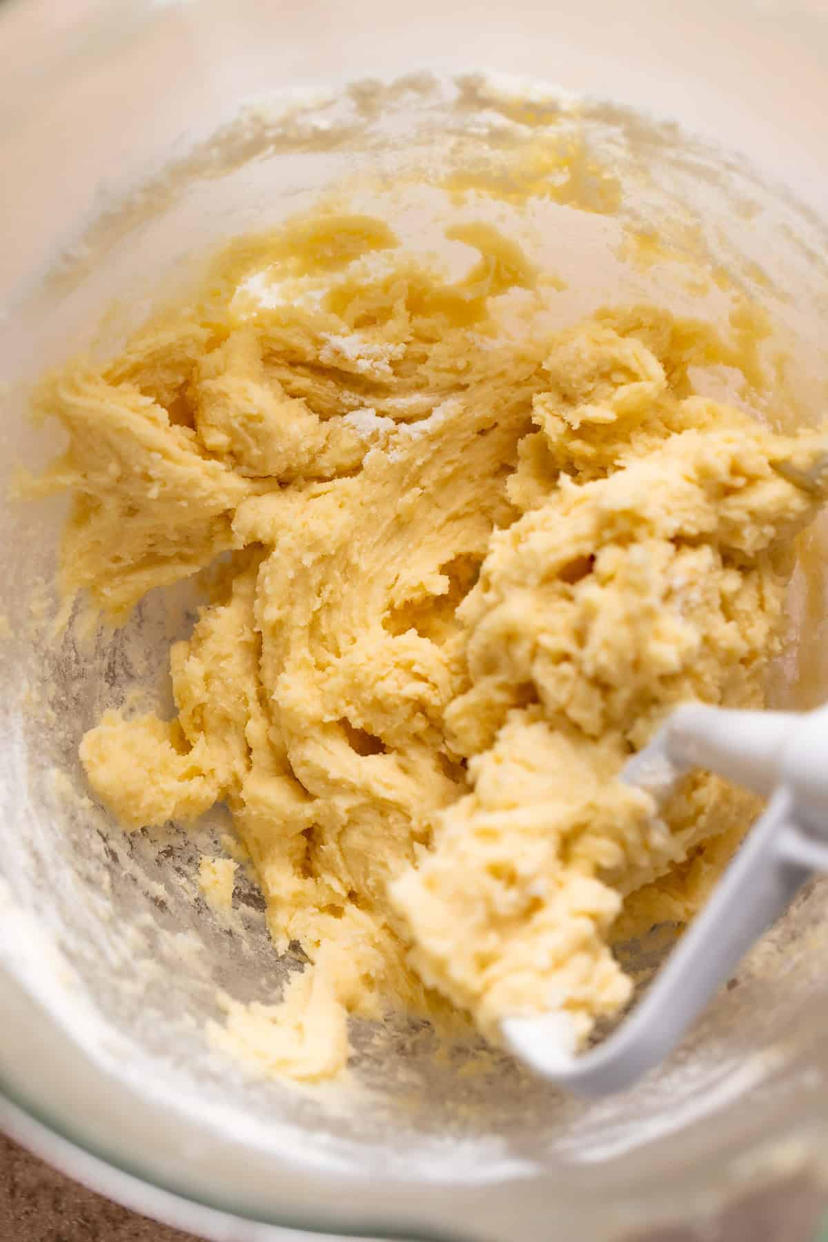 Sugar cookie dough filling in a glass mixer bowl with the paddle attachment.
