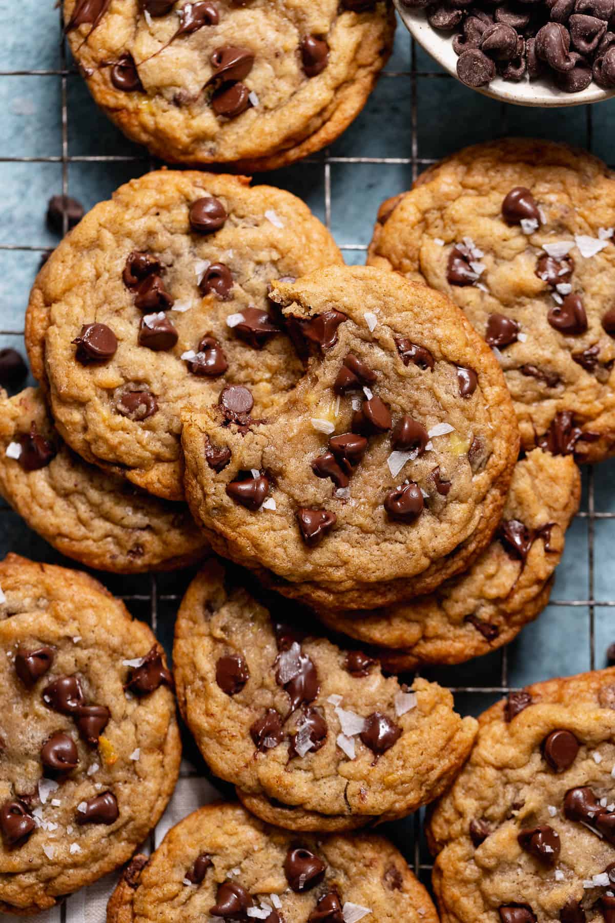 Banana bread chocolate chip cookies with soft centers in a pile on a wire rack.