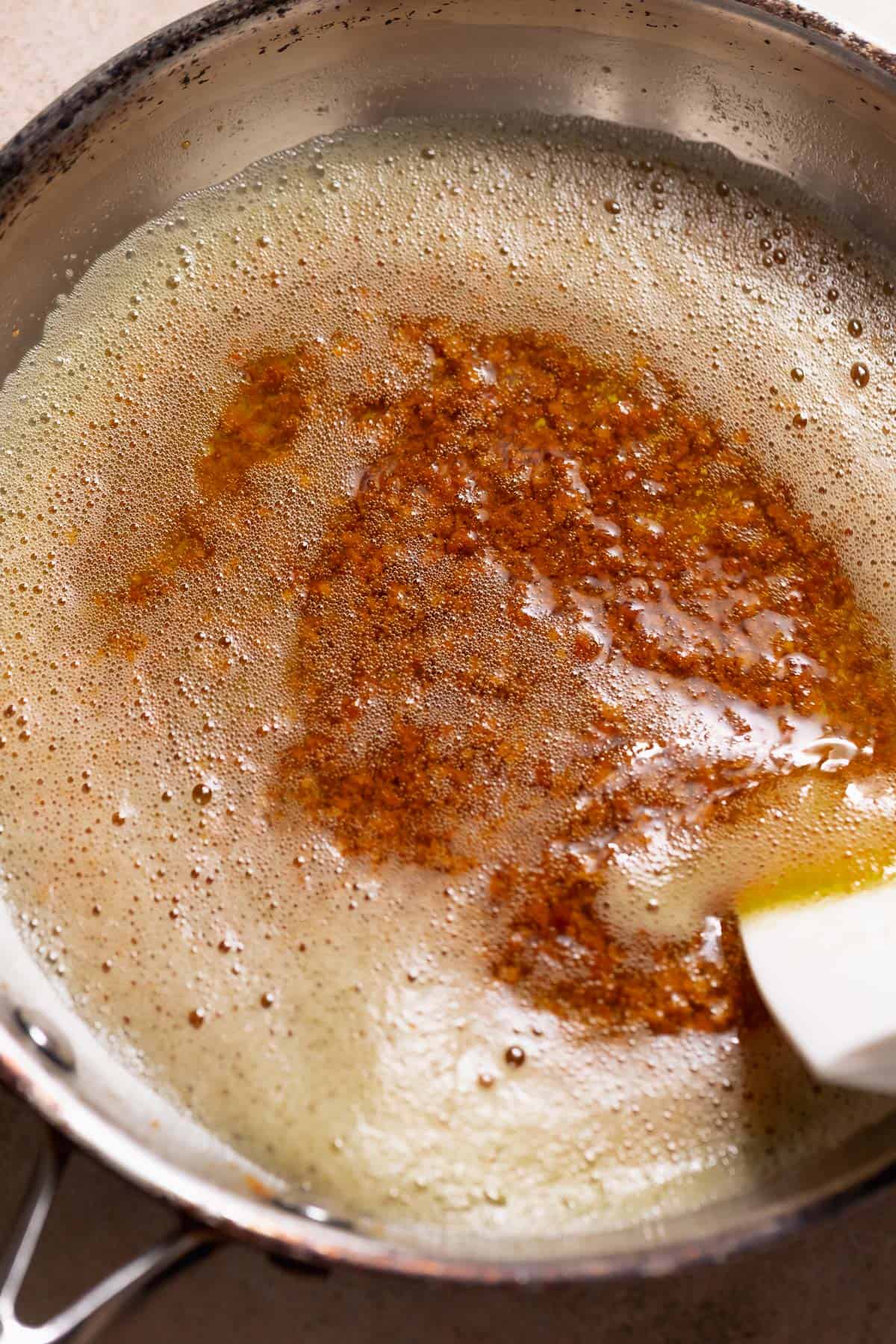 Brown butter with toasted milk solids in a stainless steel pan.