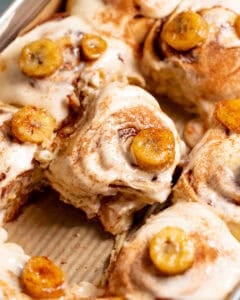 Banana bread cinnamon rolls topped with cream cheese frosting and caramelized bananas.