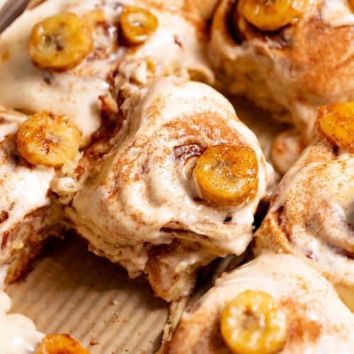 Banana bread cinnamon rolls topped with cream cheese frosting and caramelized bananas.