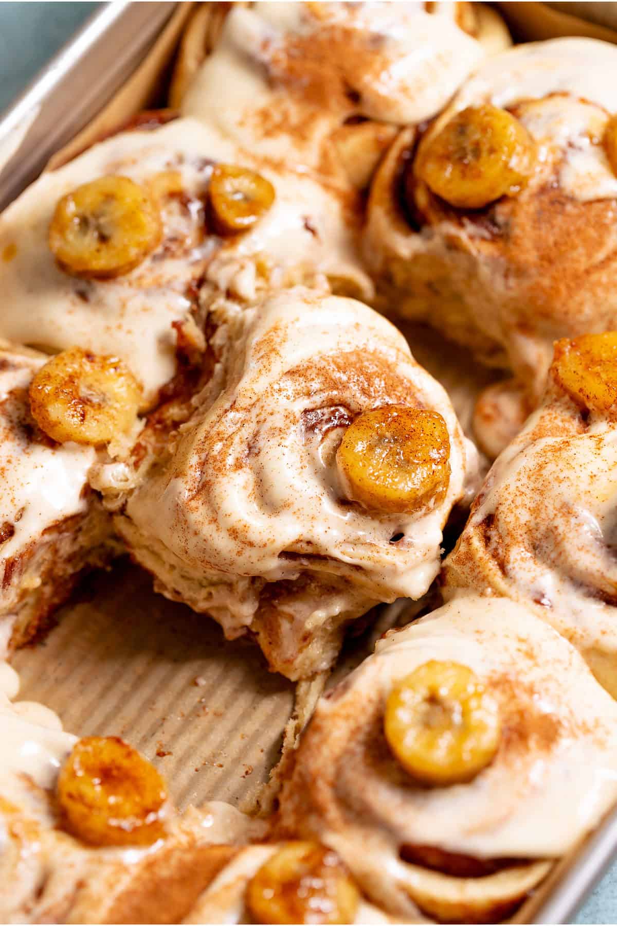 Freshly baked banana bread cinnamon rolls in a pan with golden brown swirls.