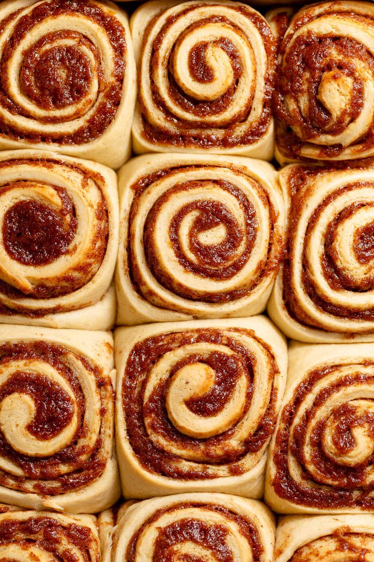 Golden banana bread cinnamon rolls baked close together in a pan.