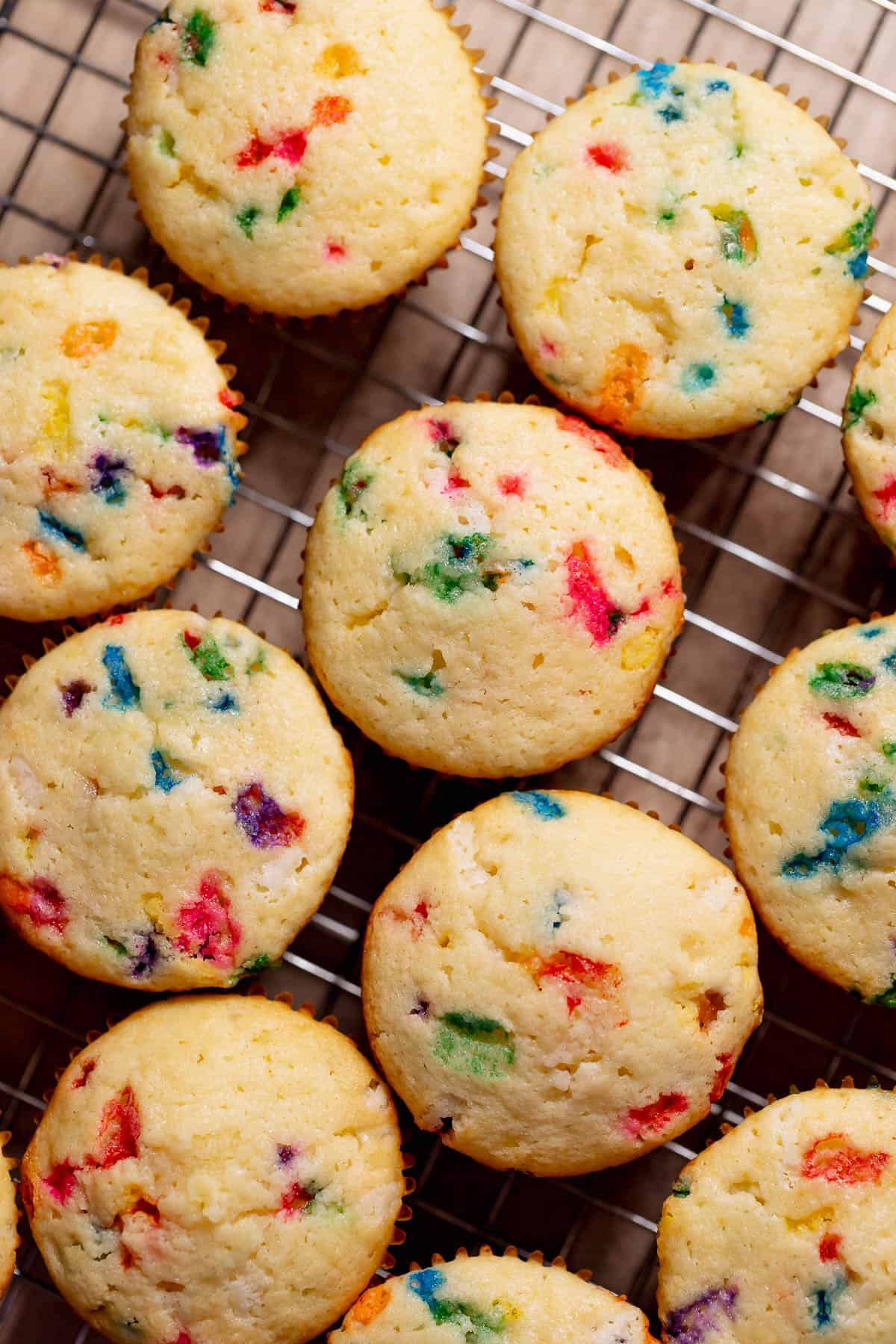 Fluffy funfetti birthday cupcakes cooling on a wire rack, showing a soft vanilla crumb with colorful rainbow sprinkles throughout.
