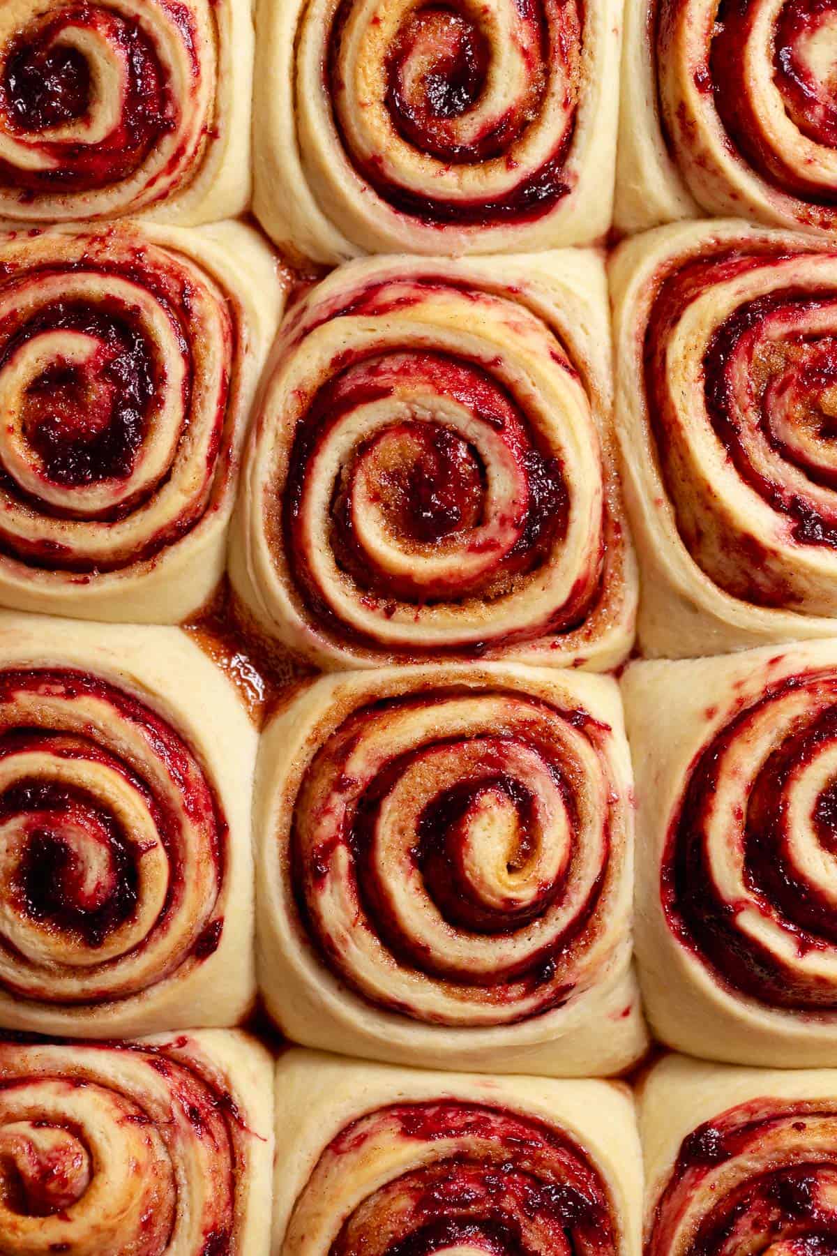 Close-up of unbaked strawberry cinnamon rolls with swirls of strawberry jam and cinnamon sugar filling.