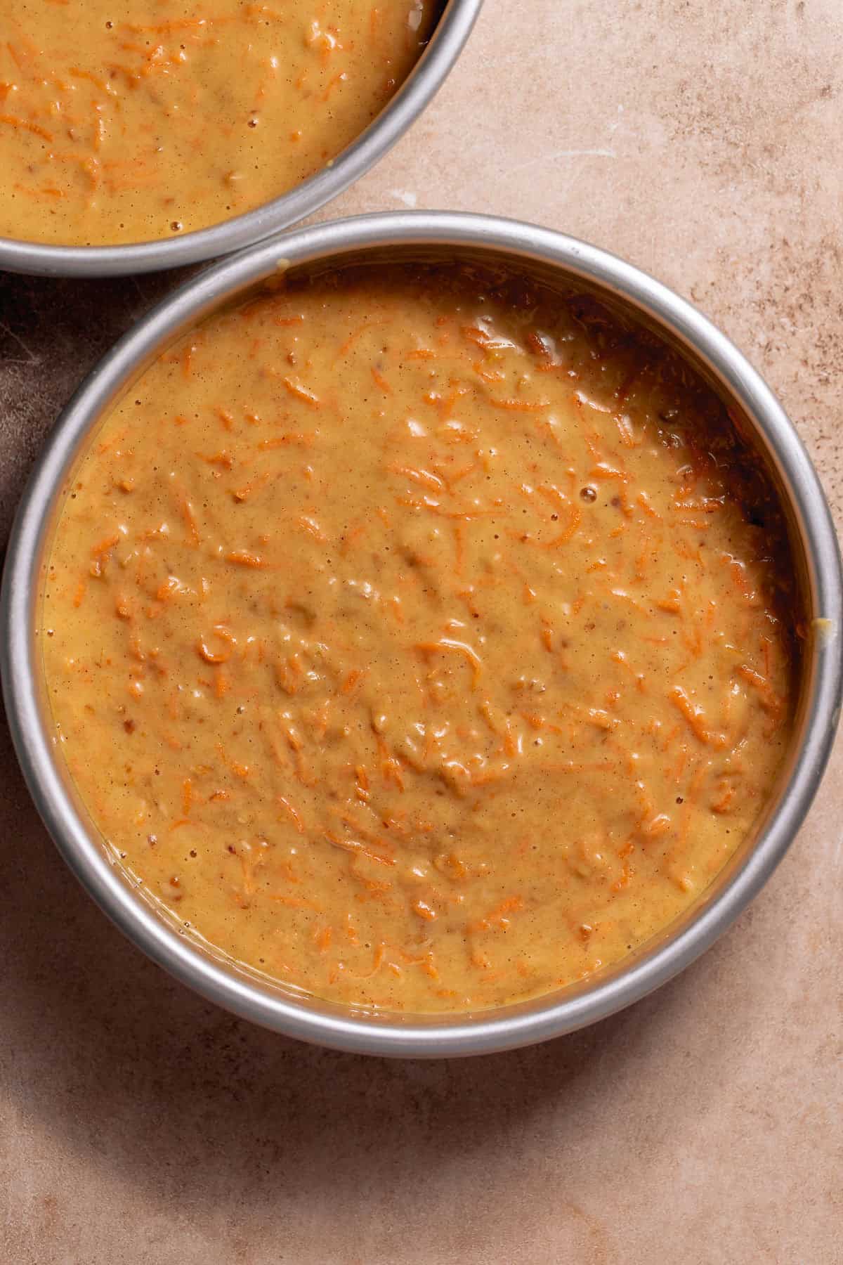 Carrot cake batter poured into round cake pans before baking.