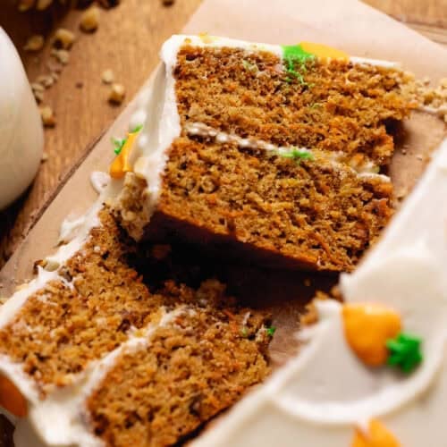Slices of homemade carrot cake with cream cheese frosting and walnuts.