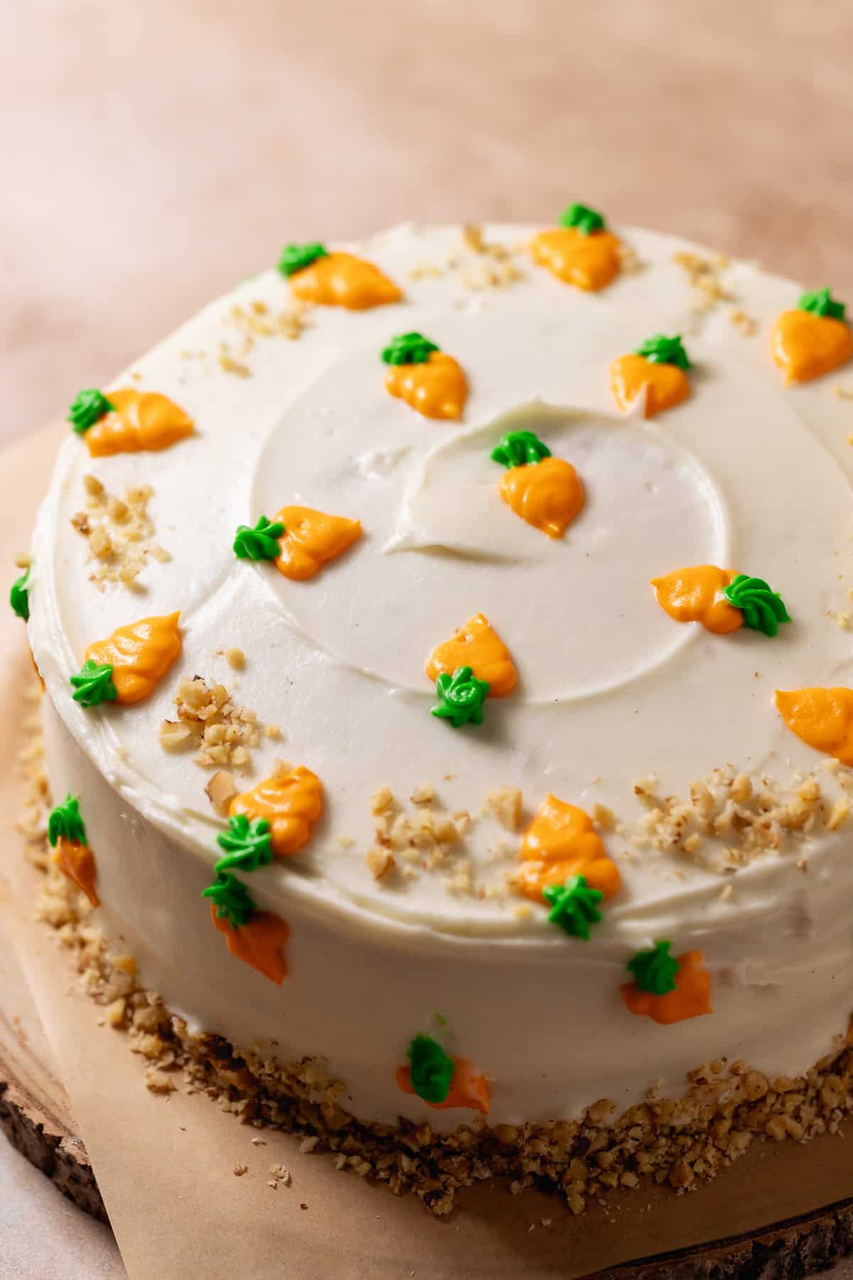 Decorated carrot cake with cream cheese frosting and piped carrot decorations.