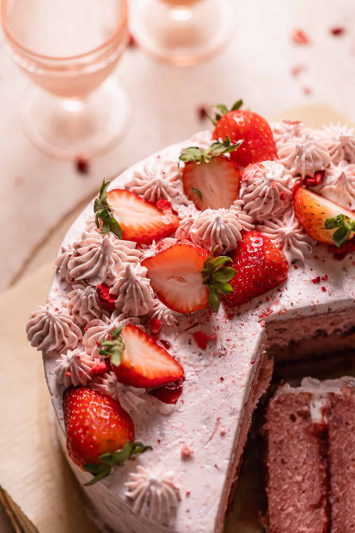 Strawberry layer cake decorated with strawberry buttercream and fresh strawberries.