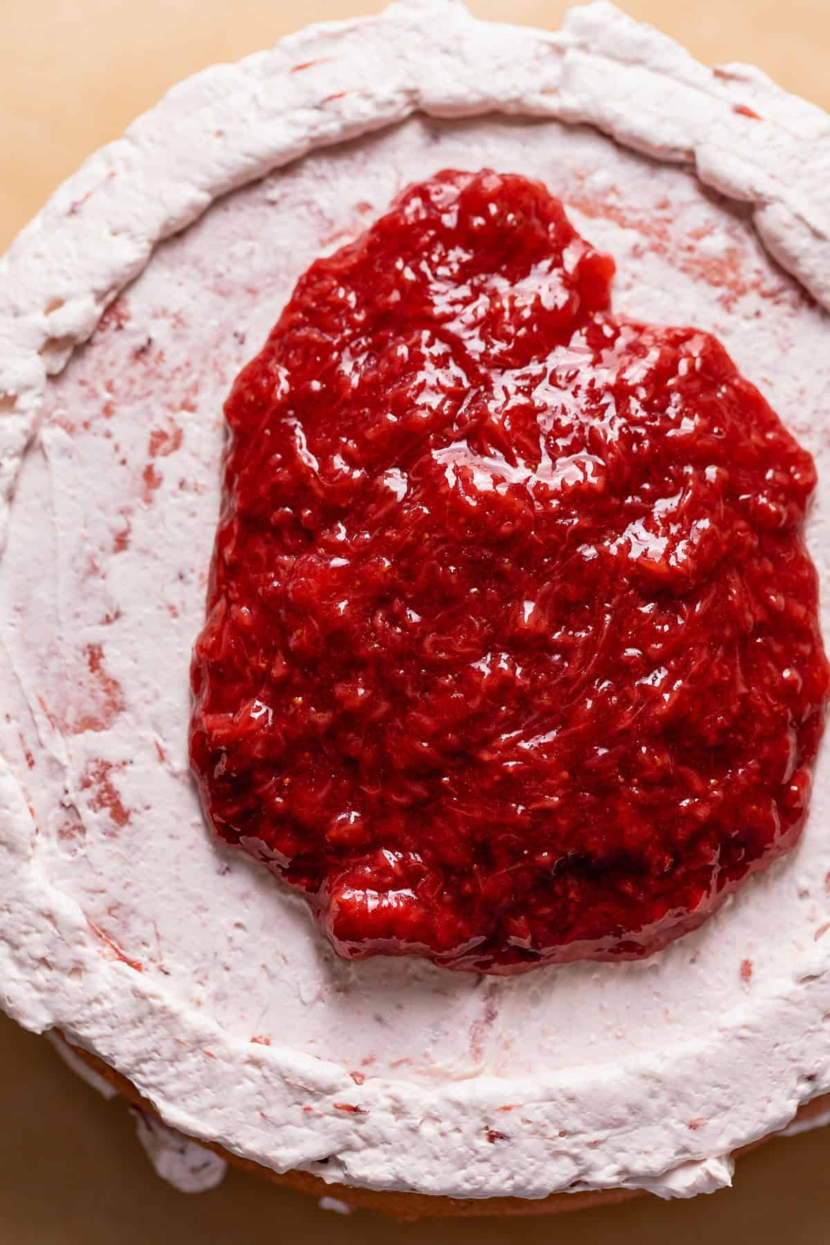 Strawberry cake layer with strawberry filling spread over strawberry buttercream.