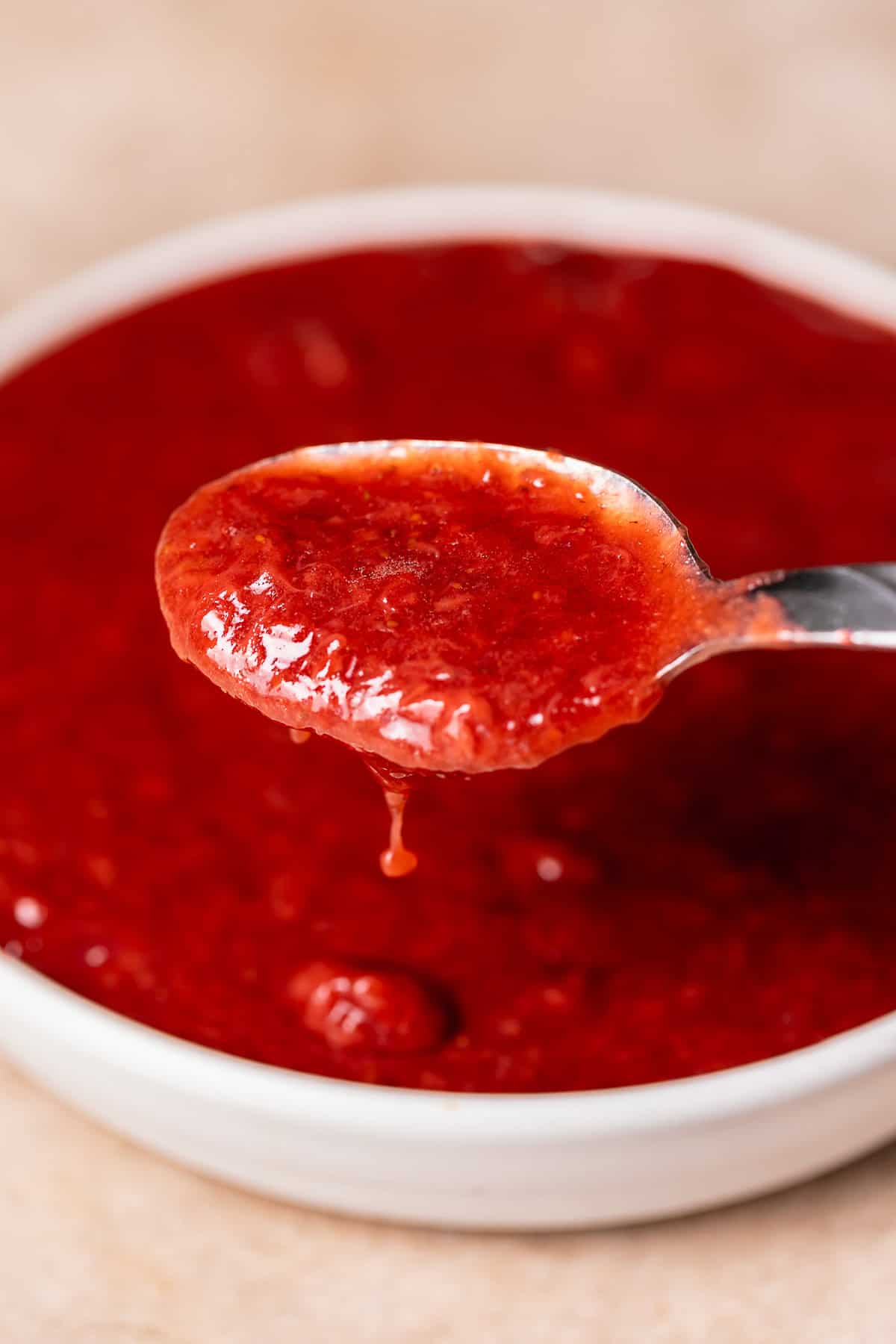 Homemade strawberry puree for the filling on a spoon.