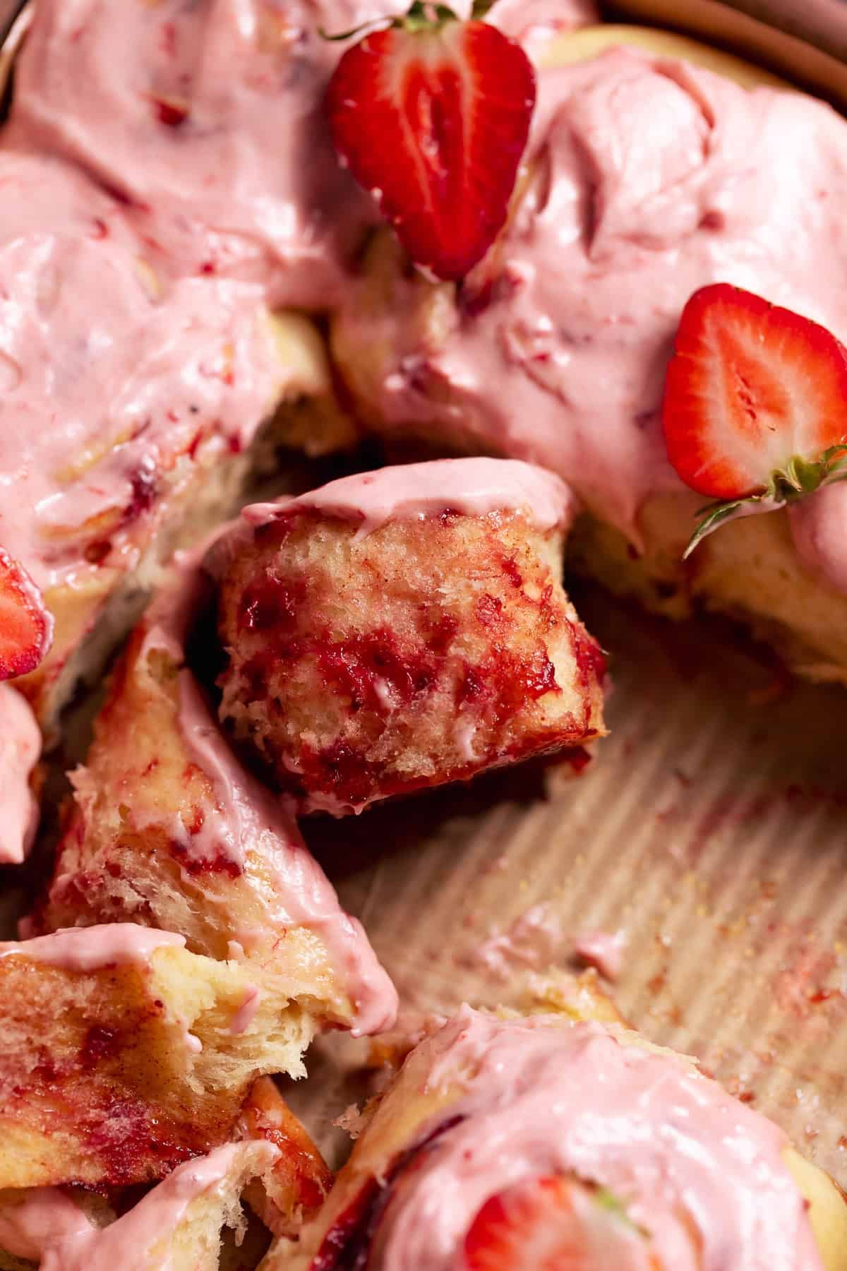 Close-up of a strawberry cinnamon roll slightly unrolled showing the soft interior and strawberry filling.