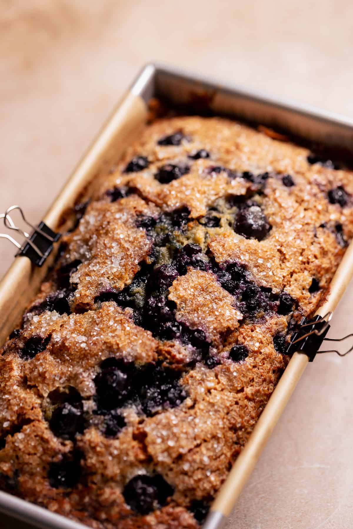 Freshly baked blueberry banana bread with a golden crackly top in a loaf pan.