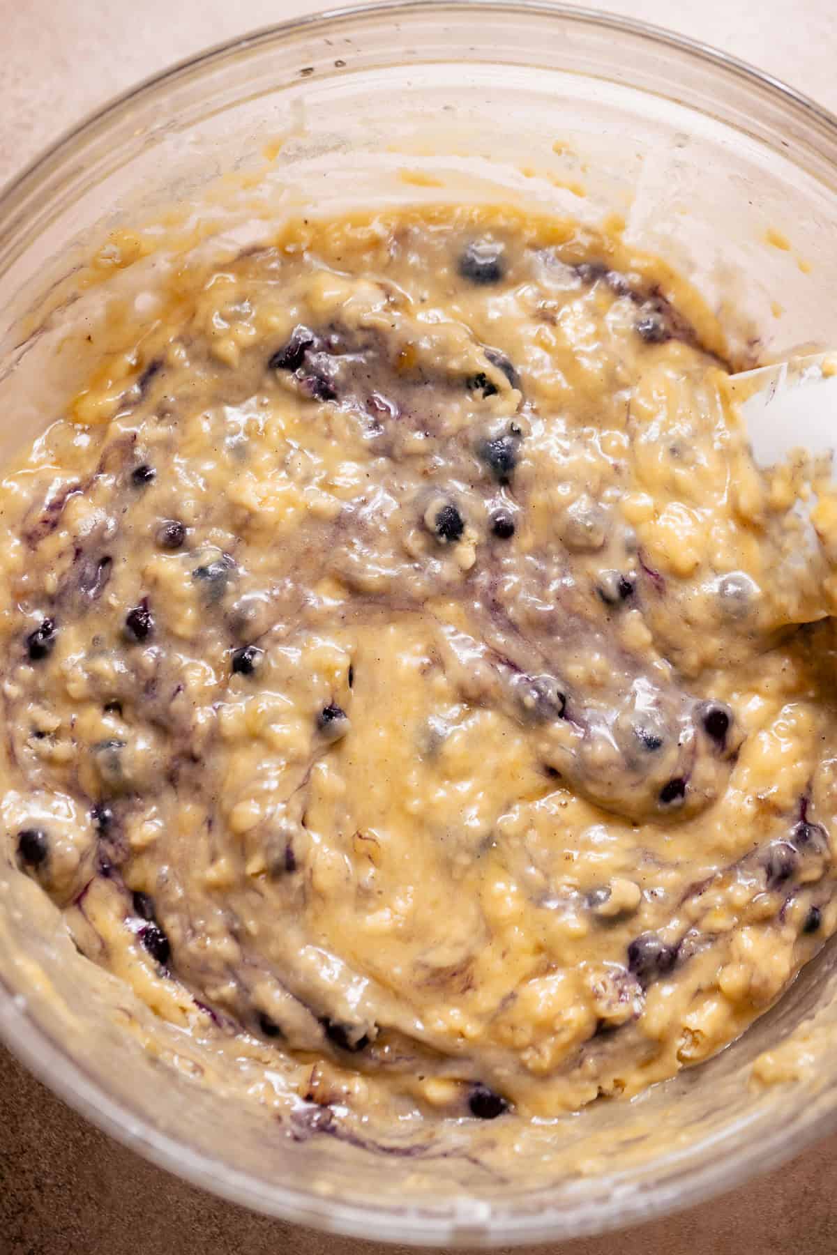Thick banana bread batter with blueberries folded into the mixture.