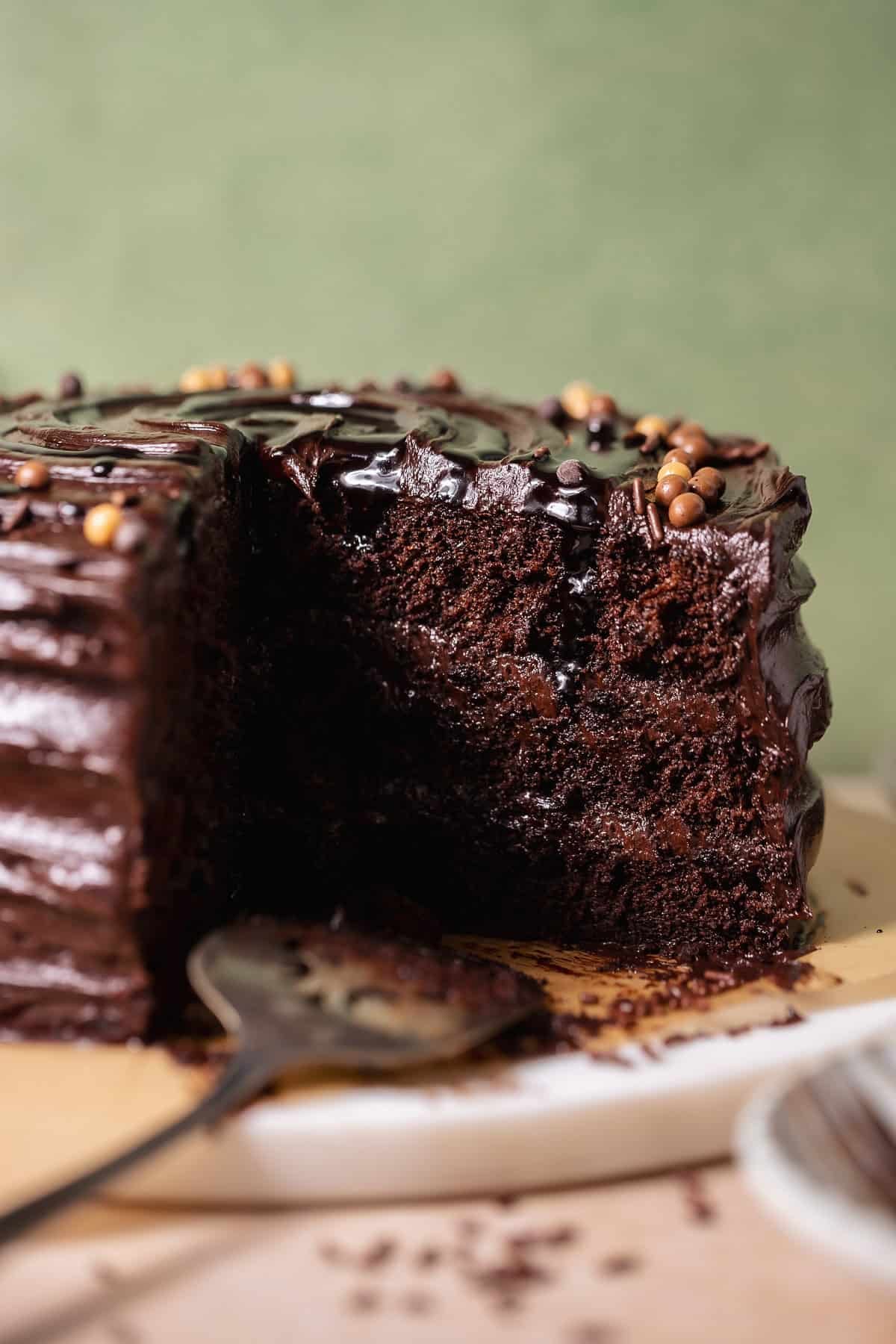 Moist chocolate cake with a slice removed showing soft crumb and glossy chocolate frosting.
