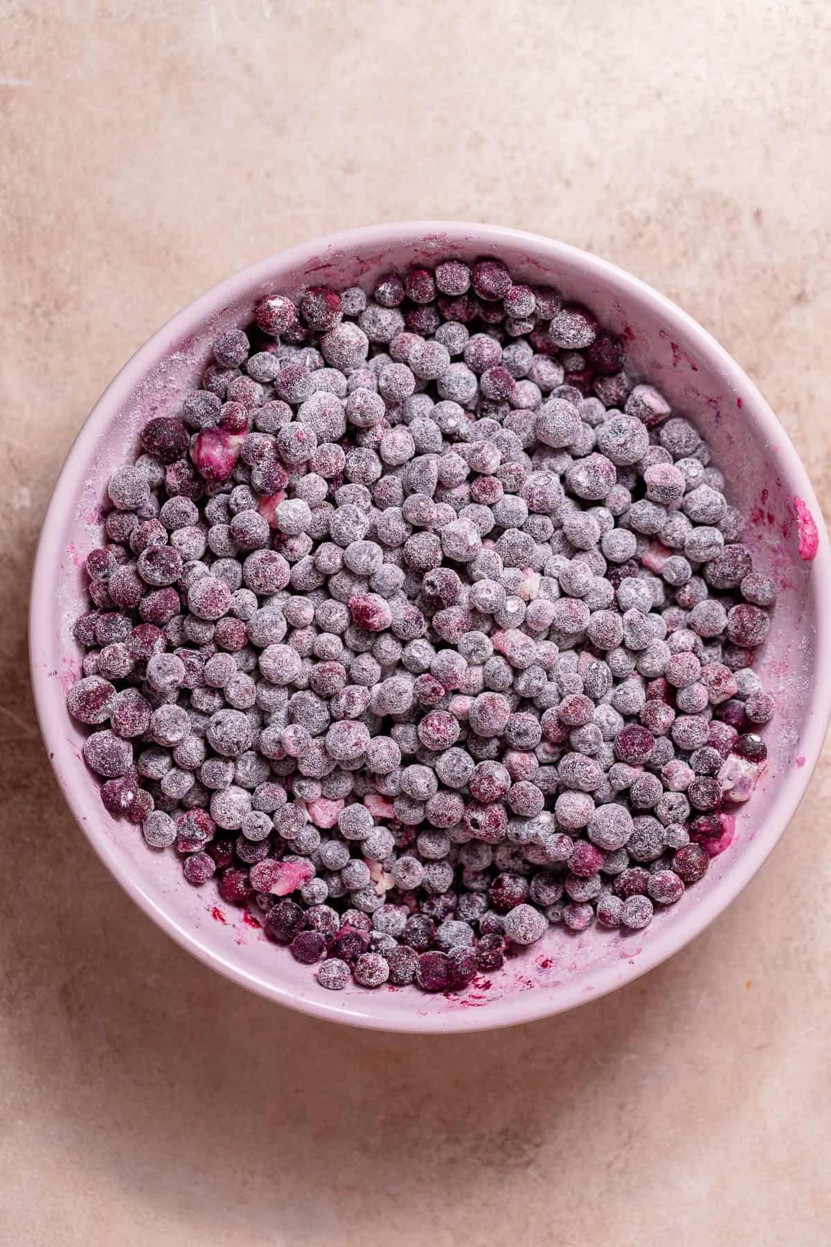 Frozen blueberries coated in flour in a bowl.