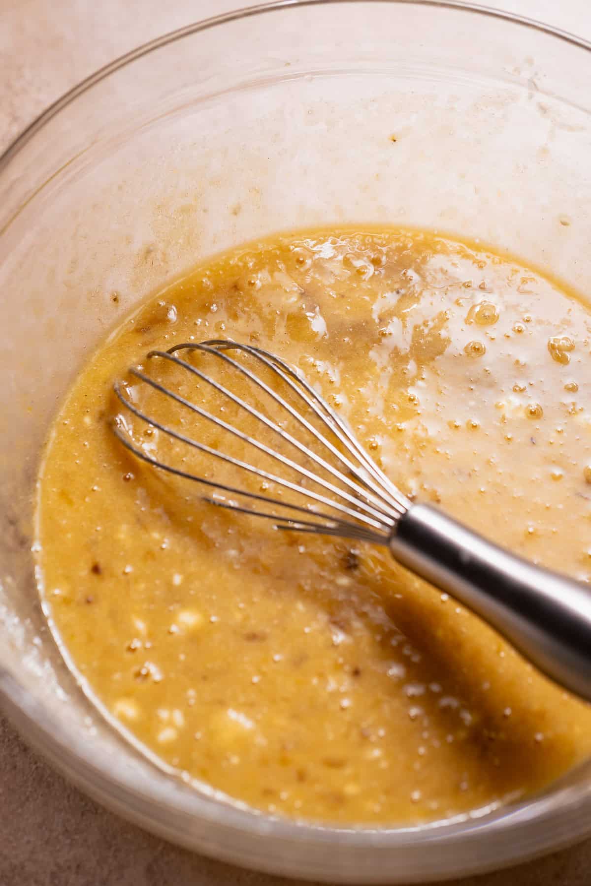Whisking mashed bananas with wet ingredients for blueberry banana bread batter.