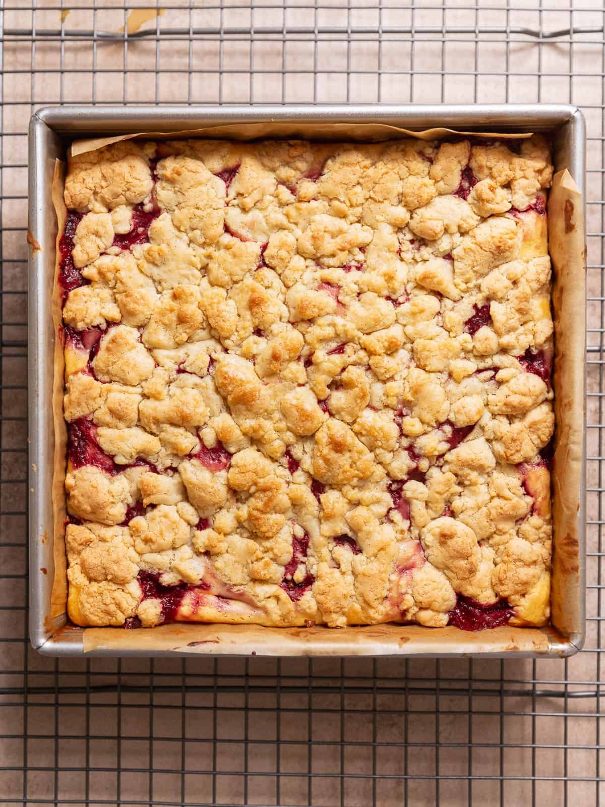 Baked strawberry cheesecake bars cooling in a square metal pan.