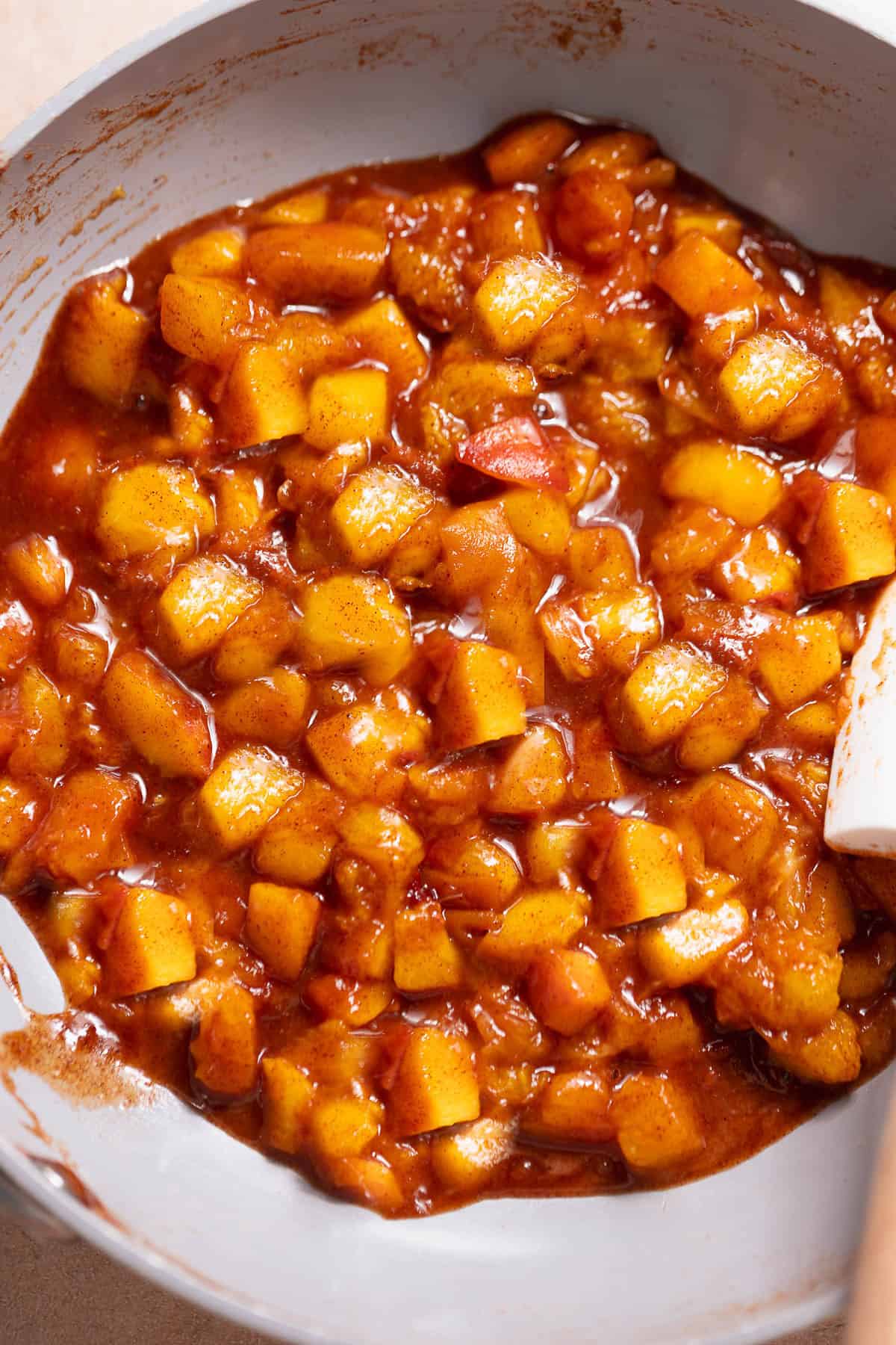 Cinnamon sugar peach filling cooking in a pan.