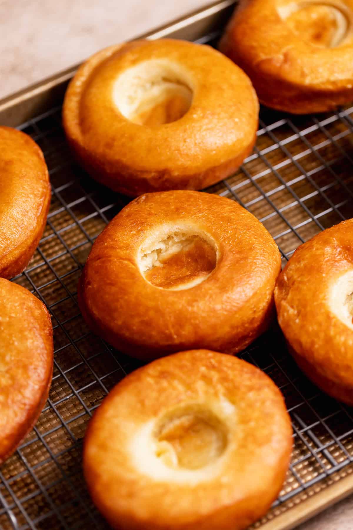 Freshly fried donuts cooling on a wire rack.