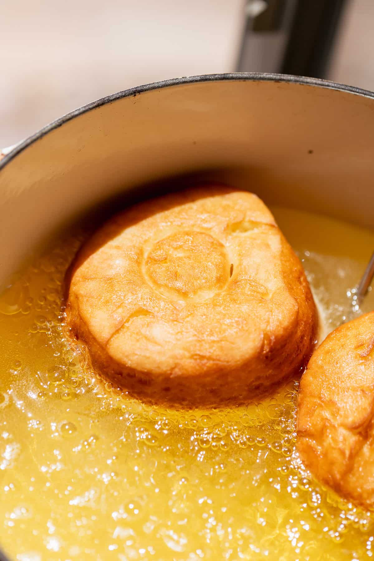 Milk bread donuts frying in hot oil until golden brown.