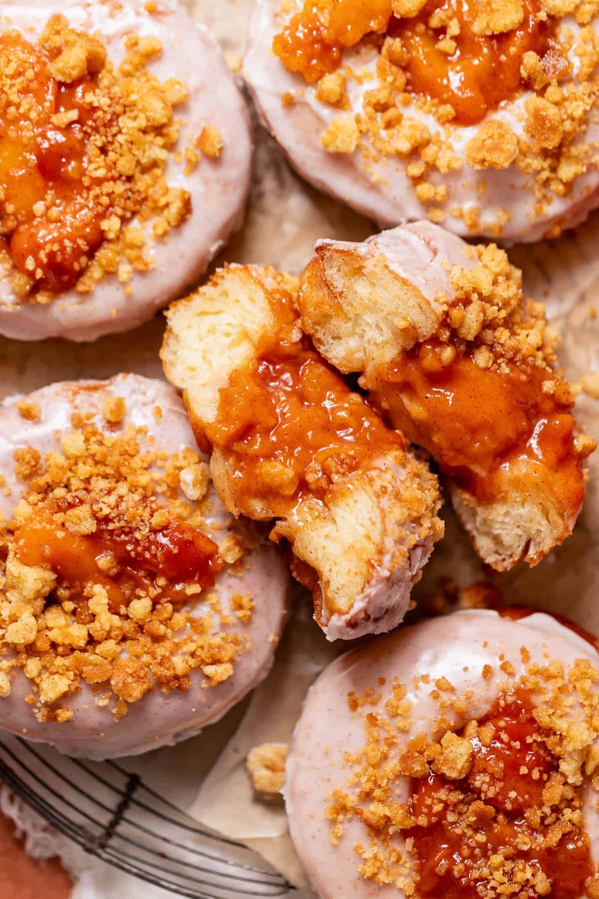 Peach donut cut in half to show the gooey peach filling on top.