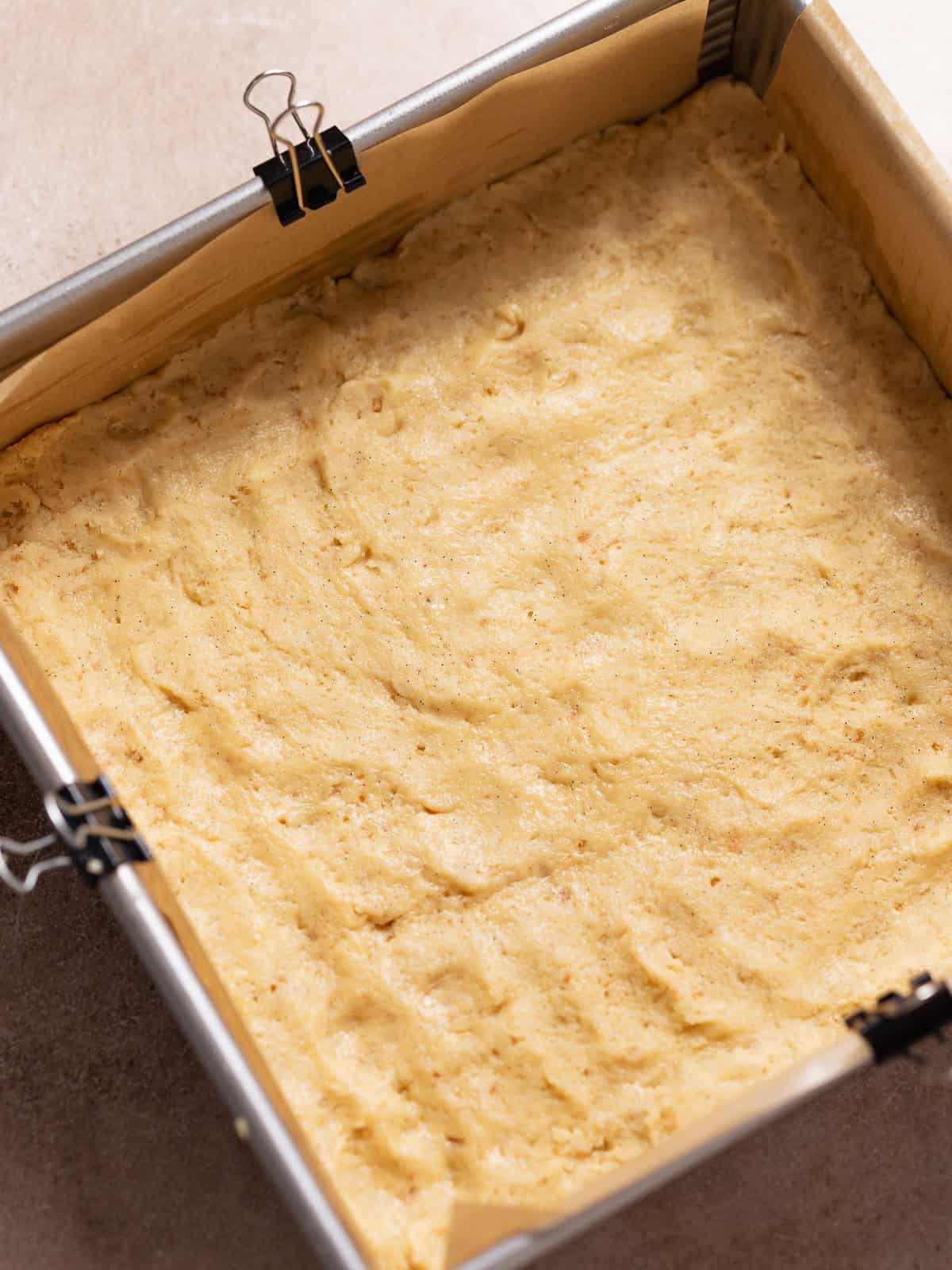 Shortbread crust dough pressed into a square baking pan.