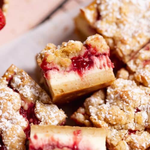 Strawberry cheesecake crumb bars dusted with powdered sugar on a wire rack.