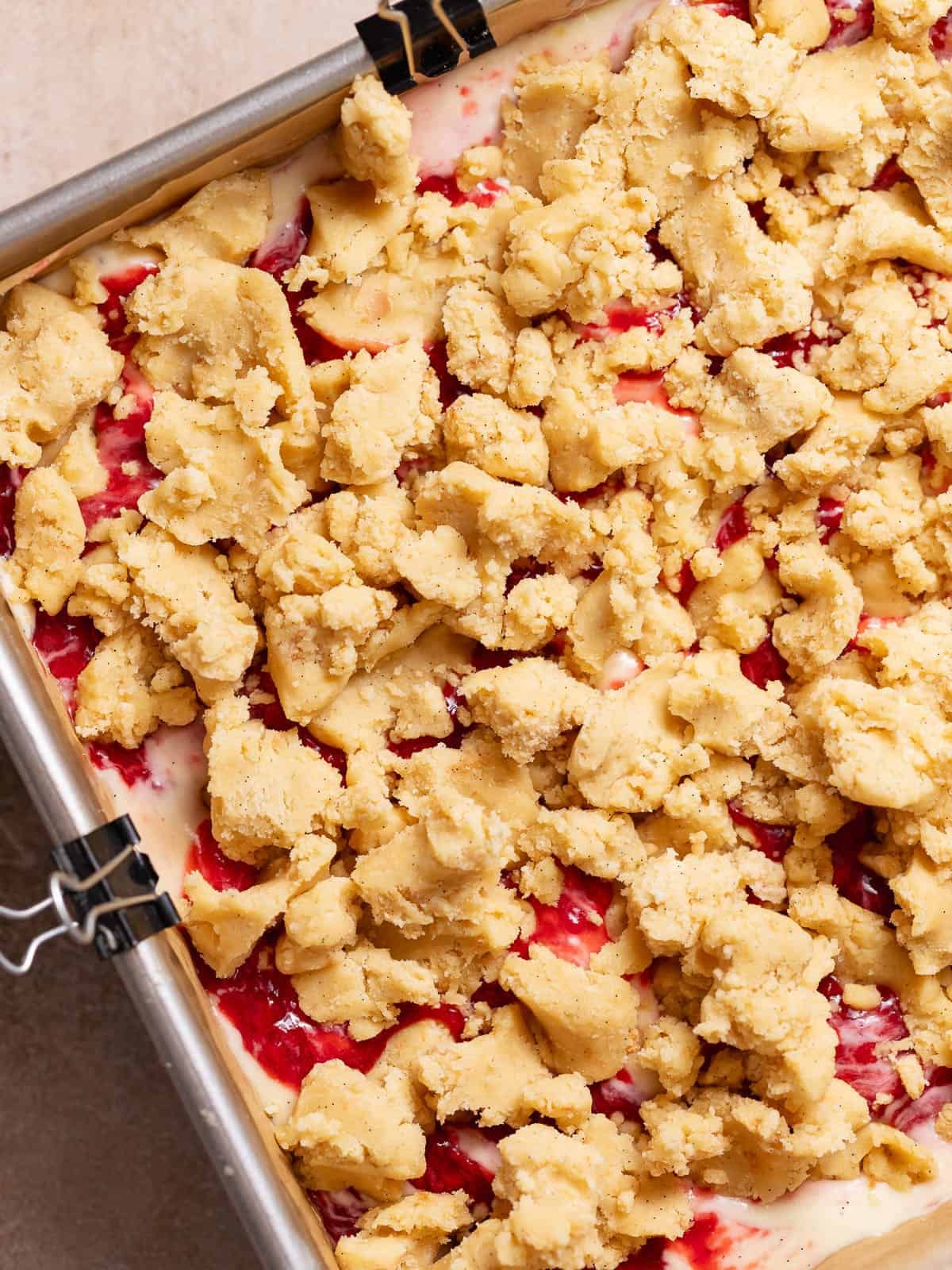 Strawberry cheesecake bars topped with crumble before baking.