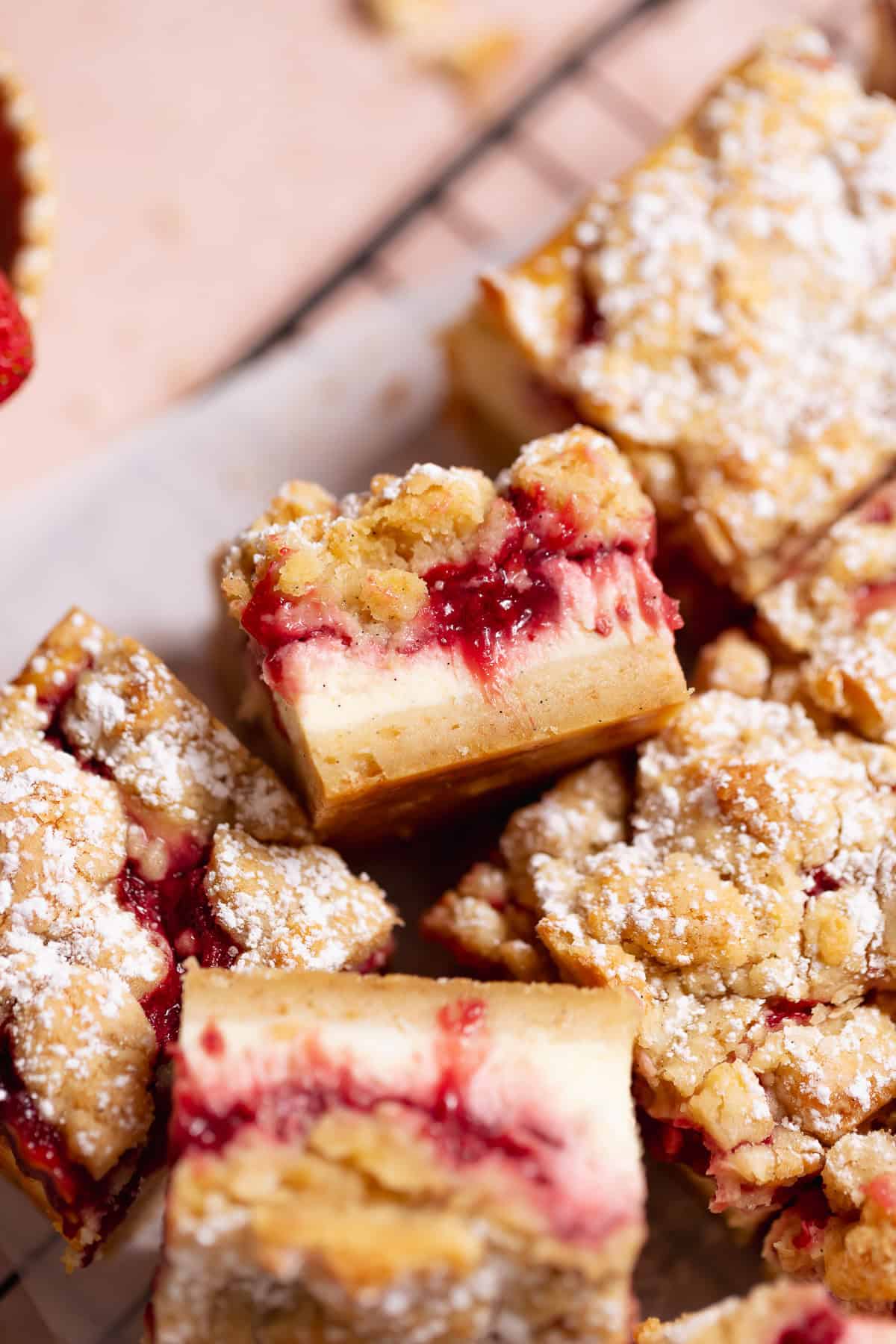 Strawberry cheesecake bar with powdered sugar on a cooling rack.