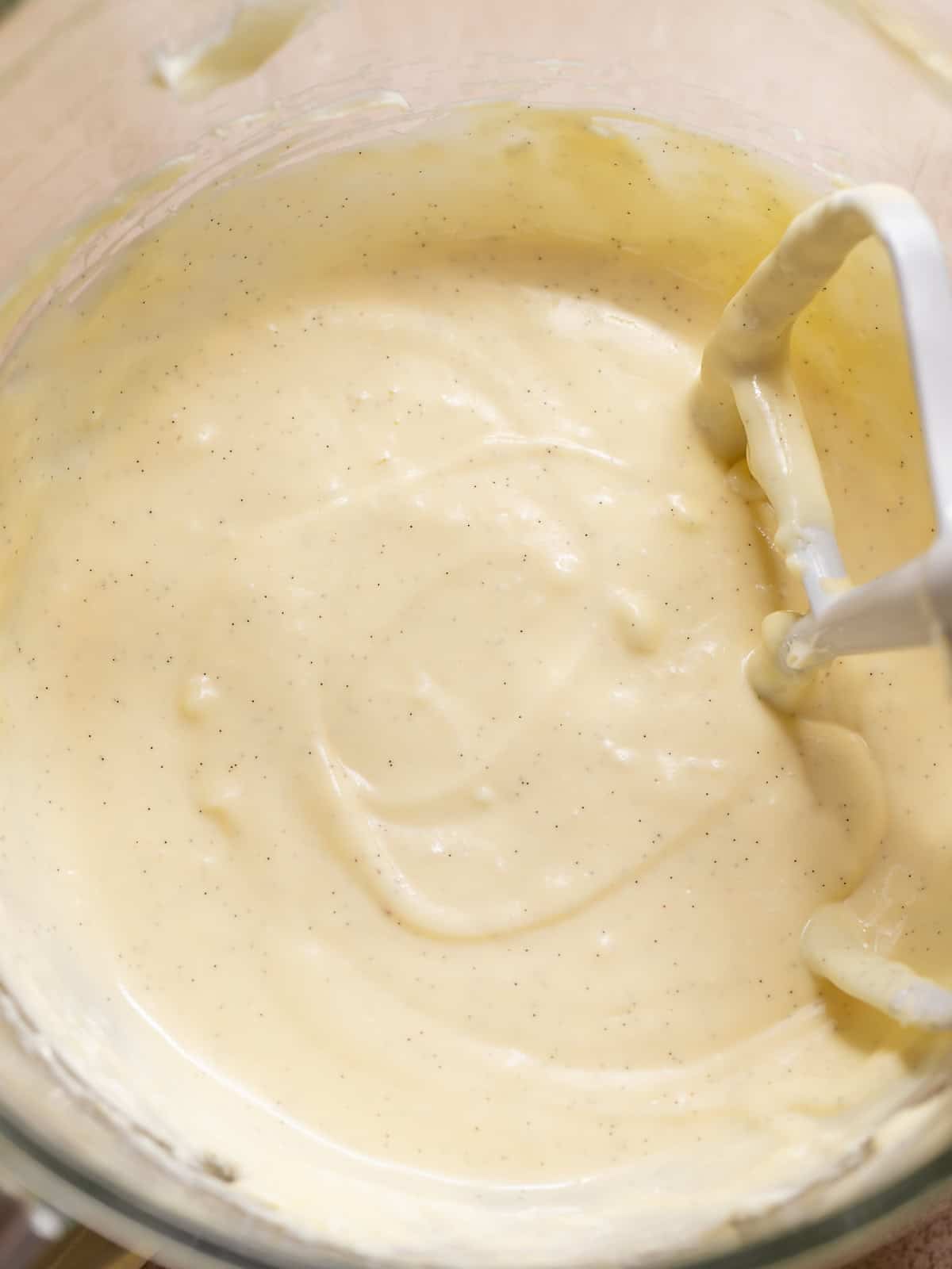 Creamy vanilla bean cheesecake filling mixed in a glass bowl.