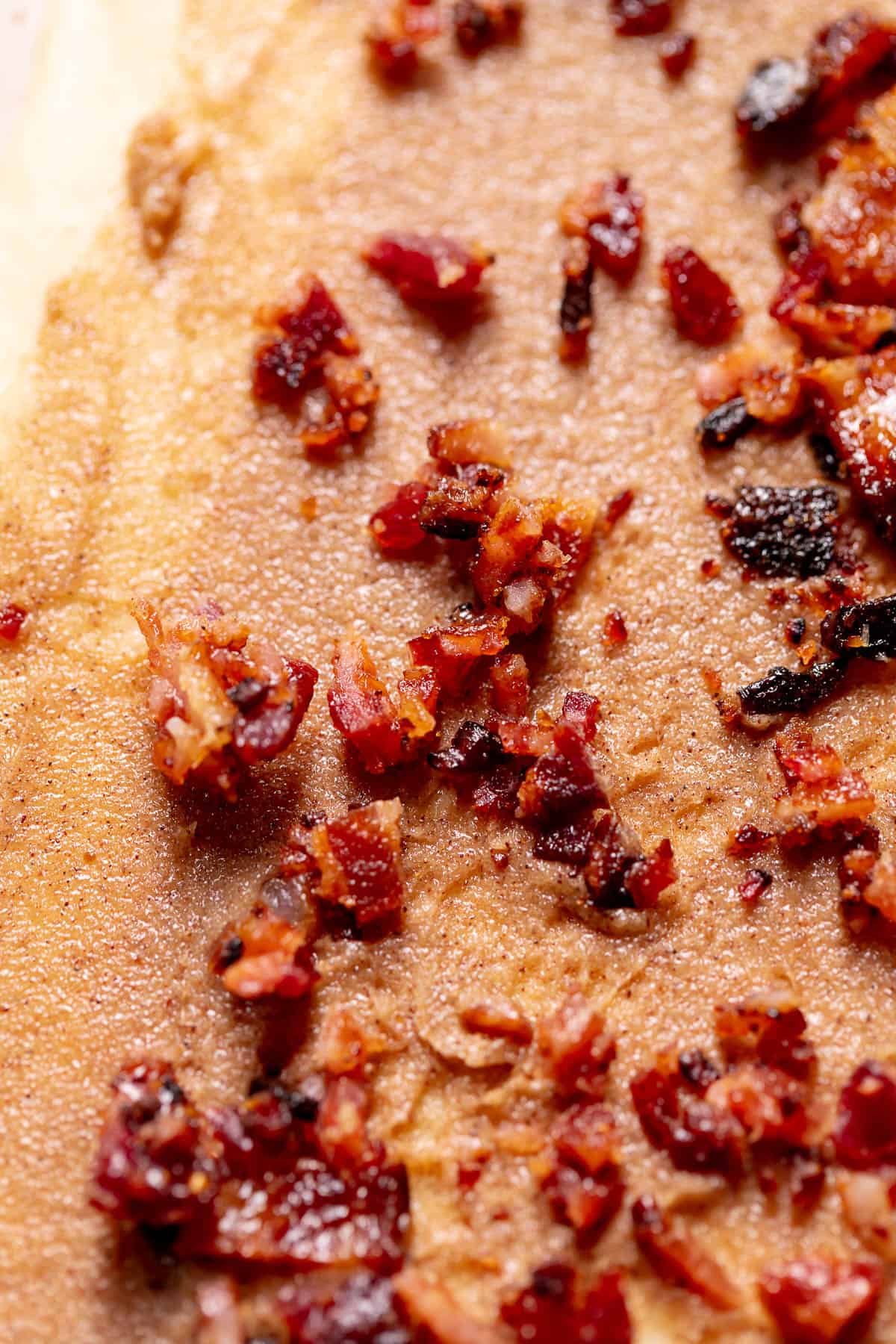 Cinnamon sugar dough topped with chopped candied bacon before rolling.