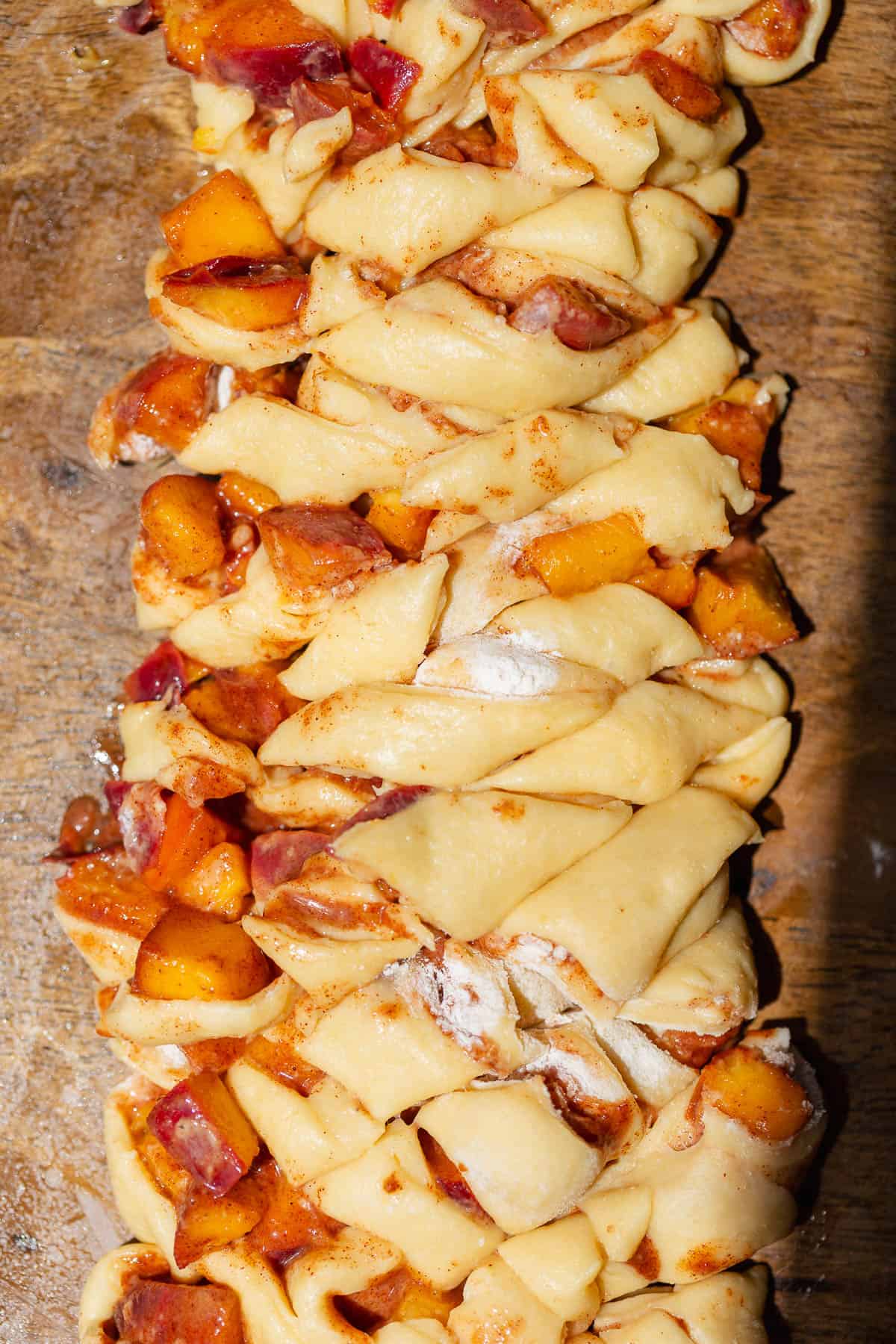 Chopped fritter dough mixed with cinnamon-spiced fresh peaches before shaping and frying.