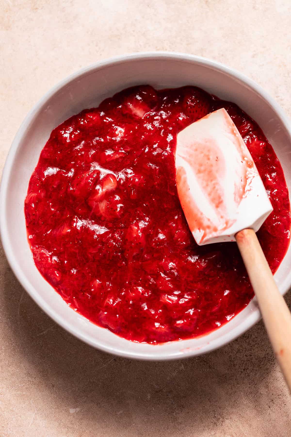 Homemade strawberry filling cooked until thick and jammy in a white bowl.