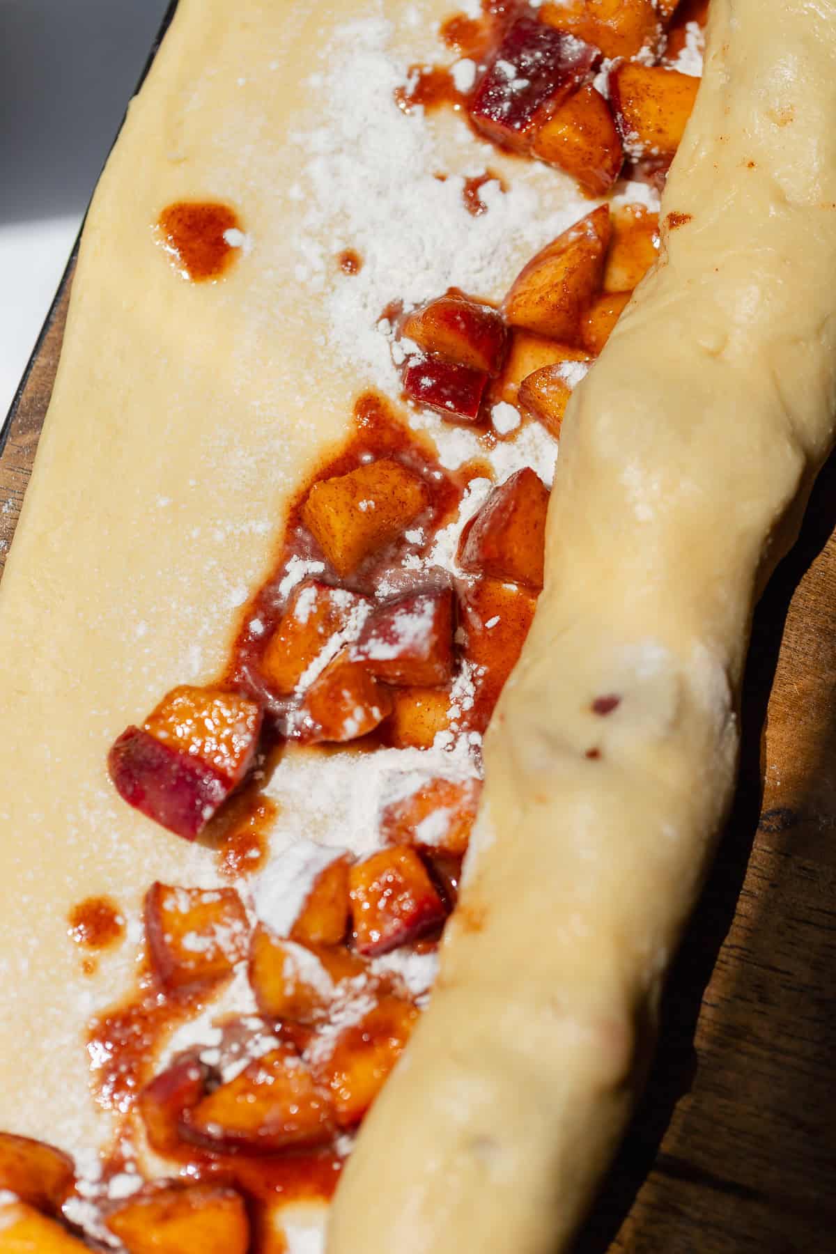 Peach fritter dough folded around fresh cinnamon peaches and shaped into a rough log.