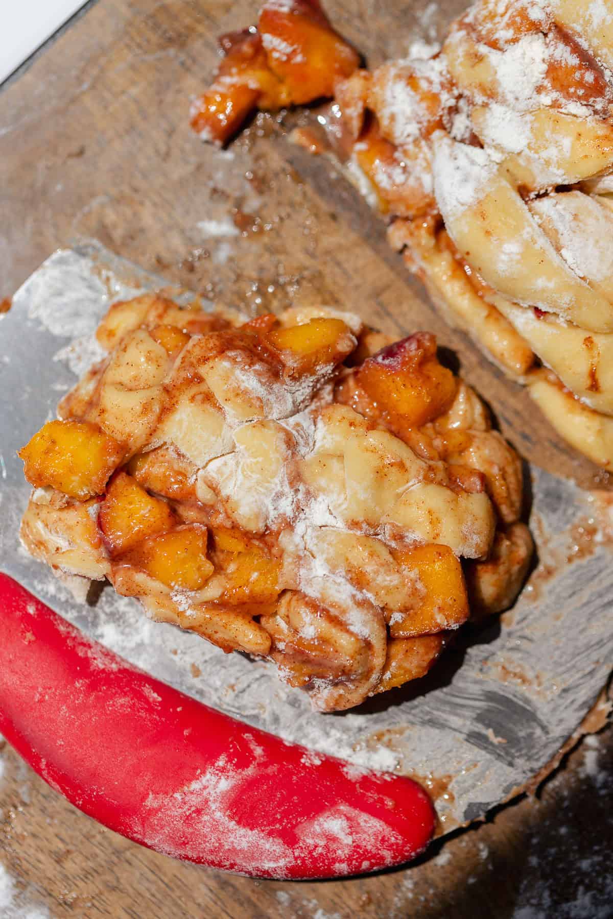 Portioned fritter dough filled with fresh peaches and coated in flour before frying.