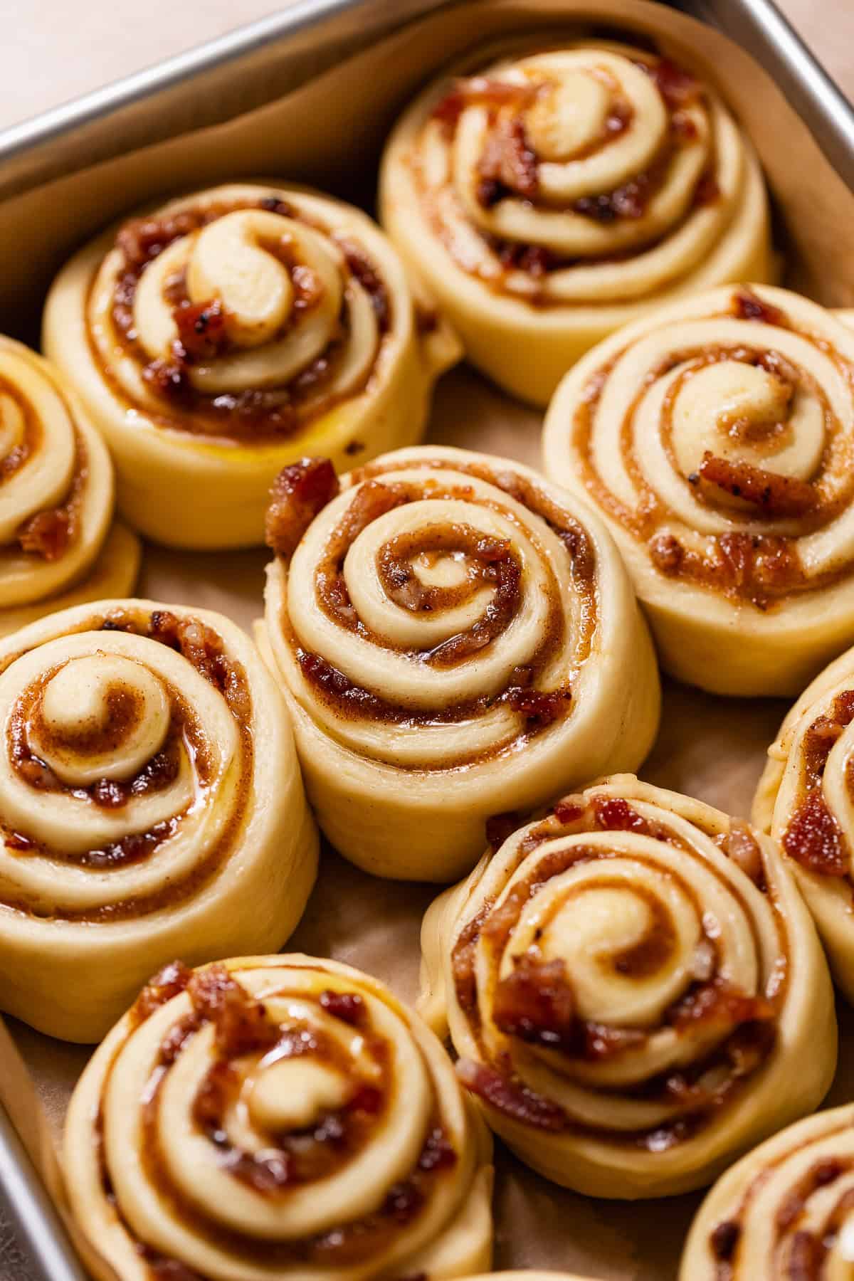 Proofed cinnamon rolls in a baking pan before baking.