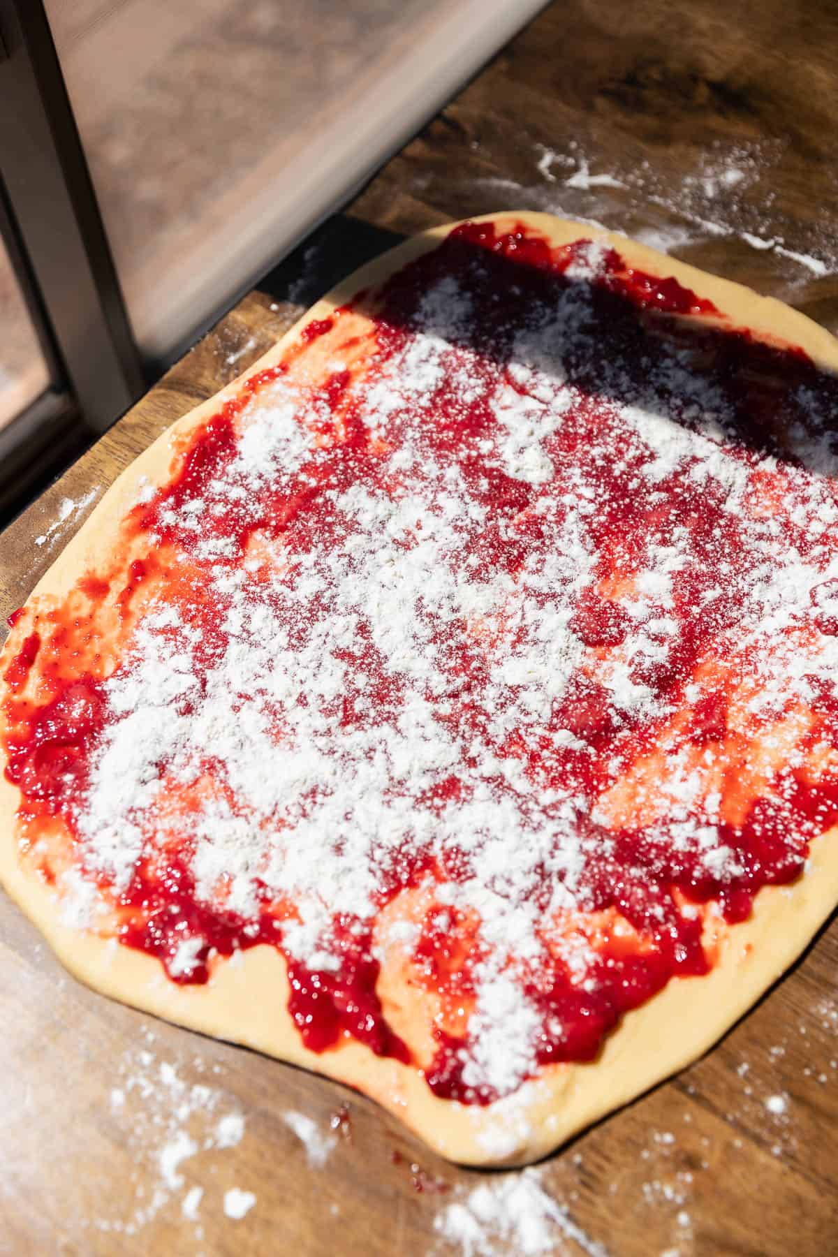 Strawberry jam spread over fritter dough before folding and shaping.