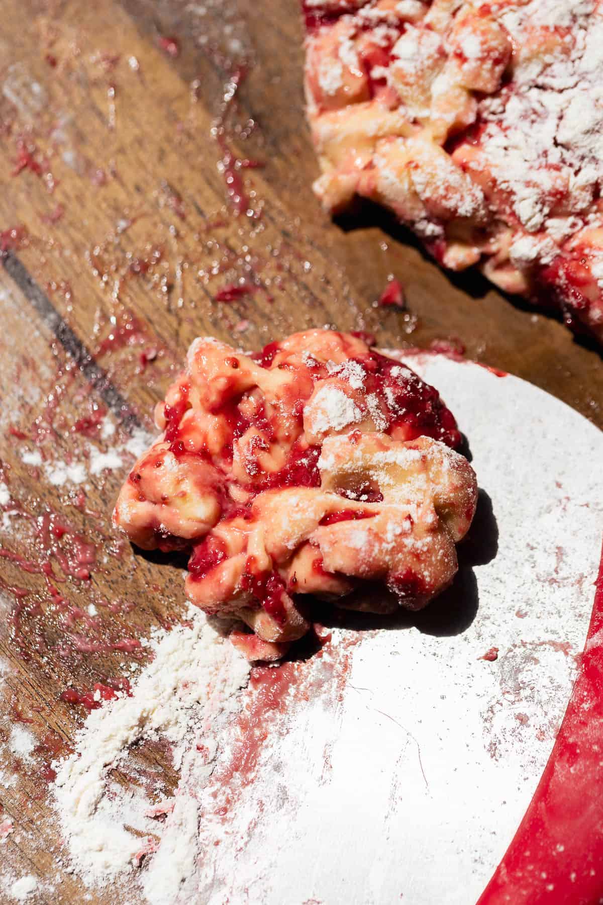 A bench scraper cutting off portions of dough to shape into fritters.